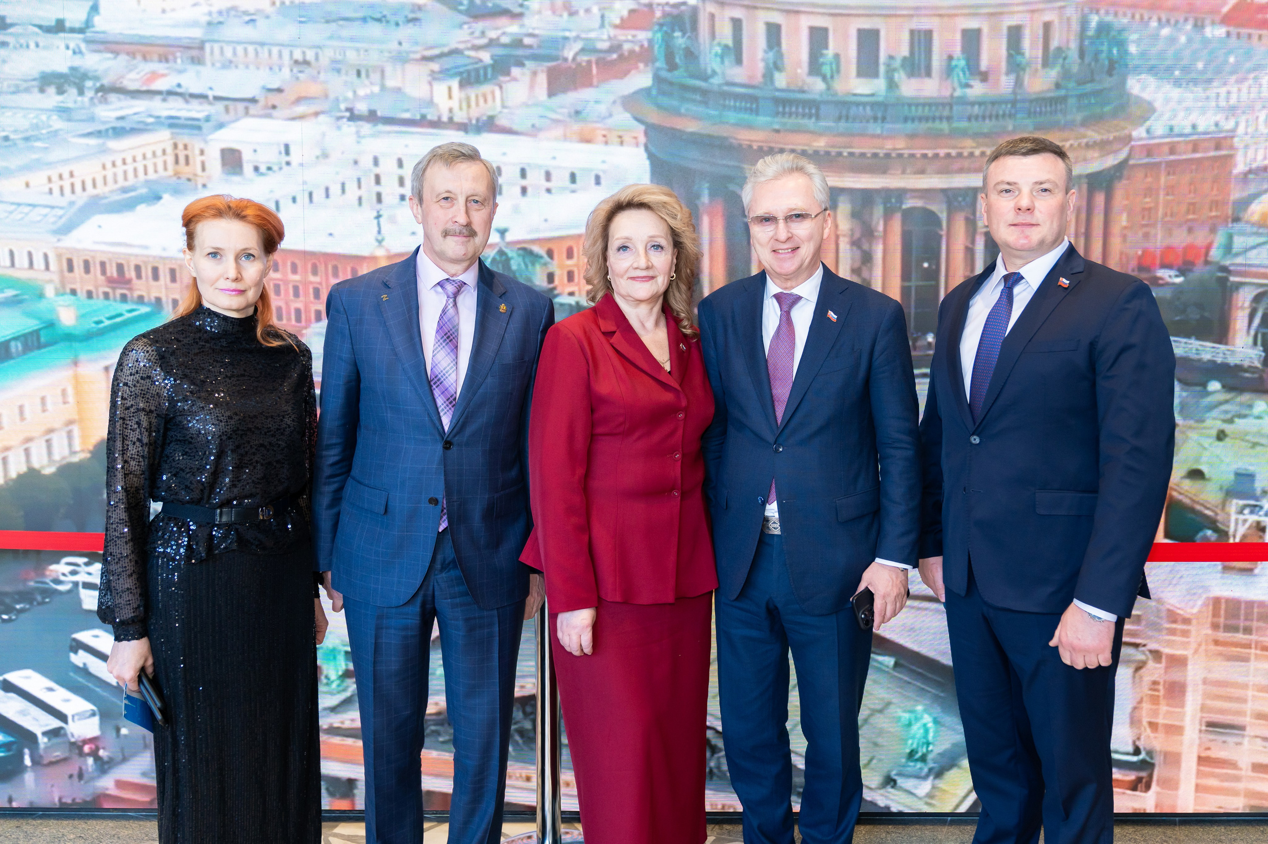 Групповое фото почётных гостей Дня местного самоуправления в Санкт-Петербурге. Мужчины и женщины в деловых костюмах на фоне вида города. Фото Евгения Мальцева.