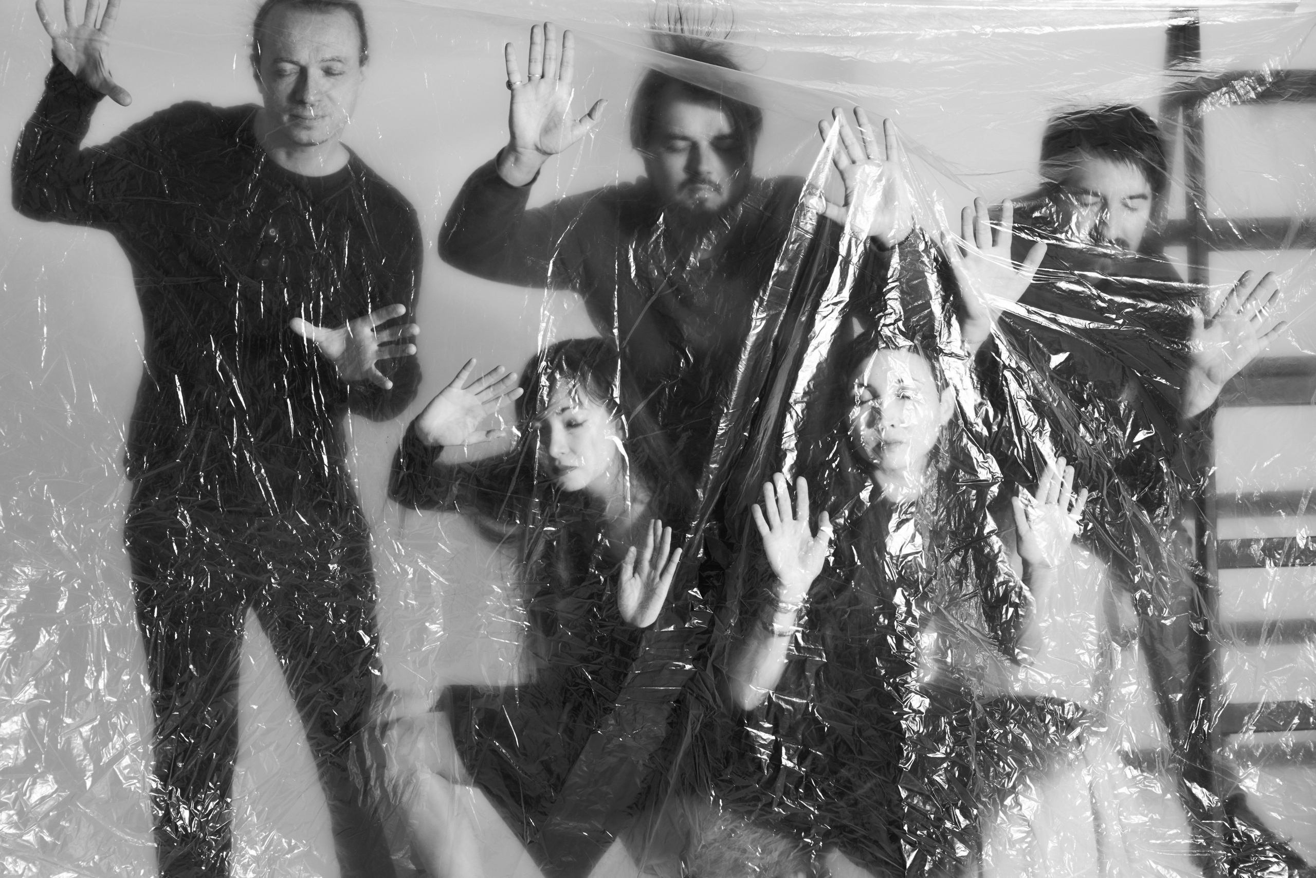 Групповое фото пяти человек с лентами и цветным светом под прозрачной полиэтиленовой плёнкой