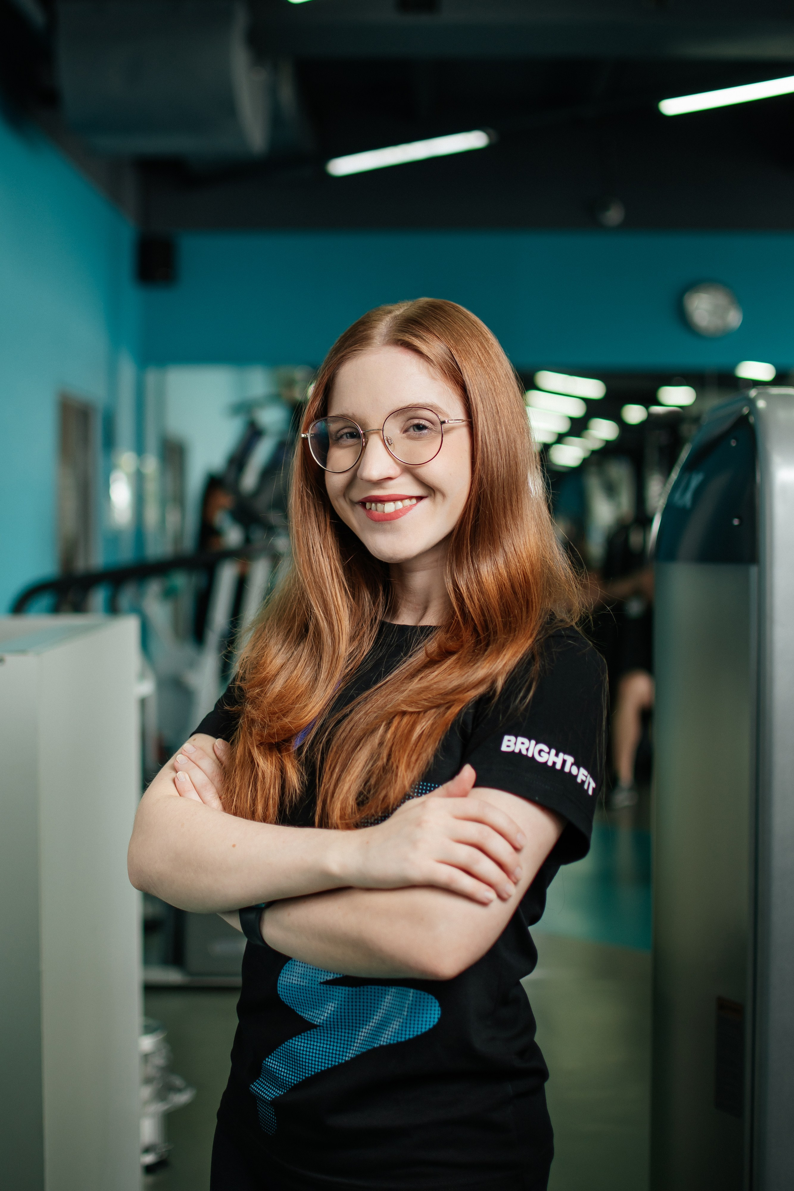 тренер фитнес-клуба на фоне зала фитнес-клуба