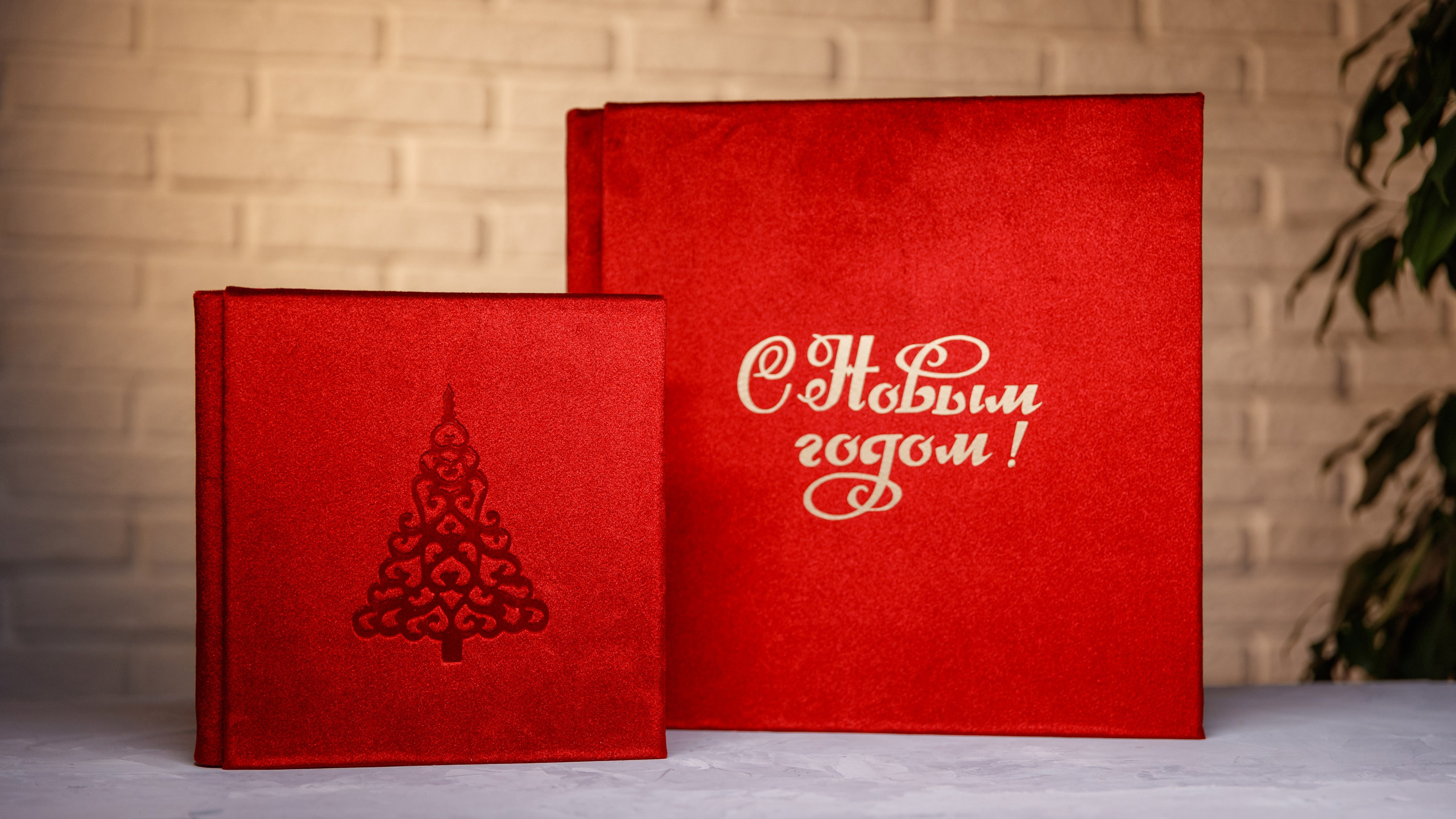 Новогодние фотокниги из красного бархата с тиснением елочки и надписью С Новым годом на русском языке.
