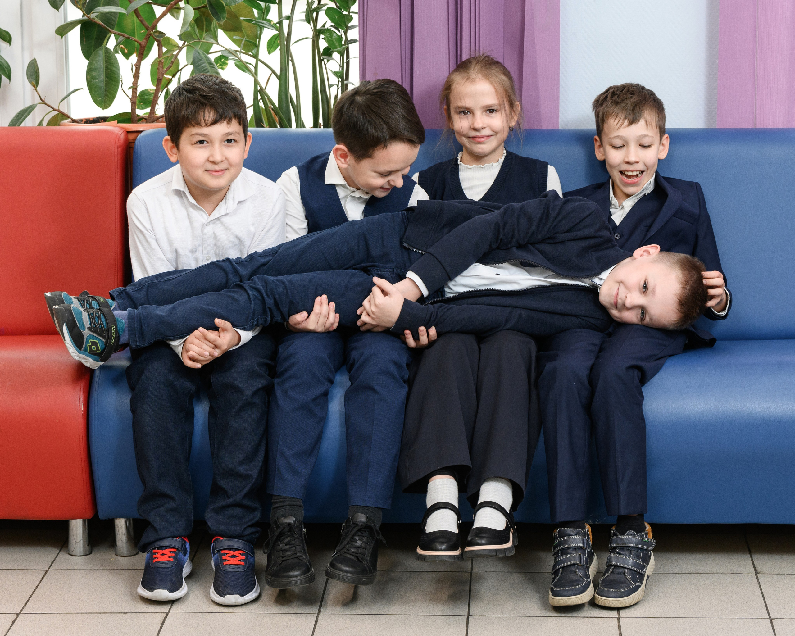 Пятеро учеников на диване в школьном коридоре 