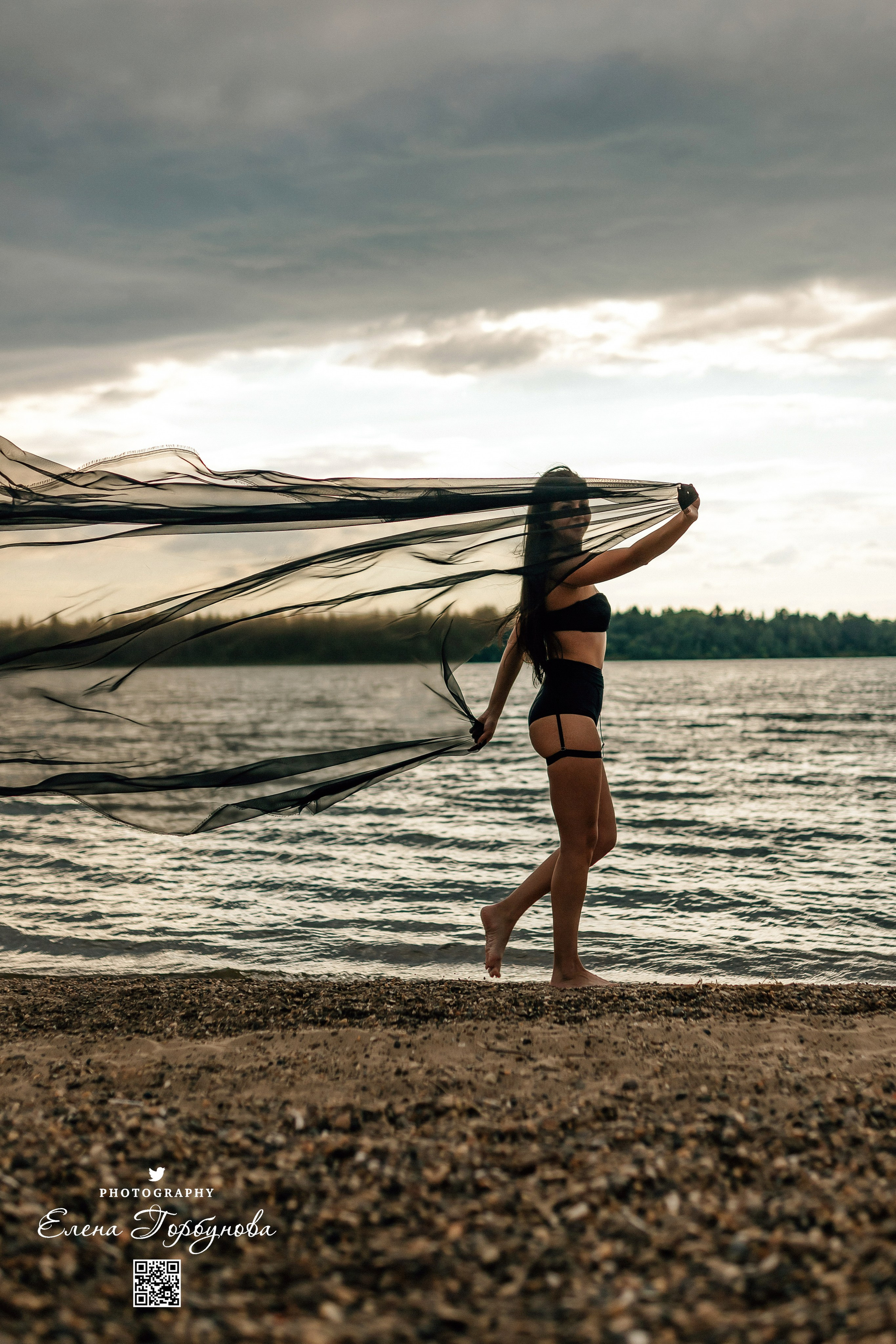 Фотосессия с черной тканью. Легкая черная вуаль летит на вертру. Фотосессия у реки черная серия с тканью. Девушка укуталась в черную ткань. Прогулка по набережной. Песок, речка, модель в черном.