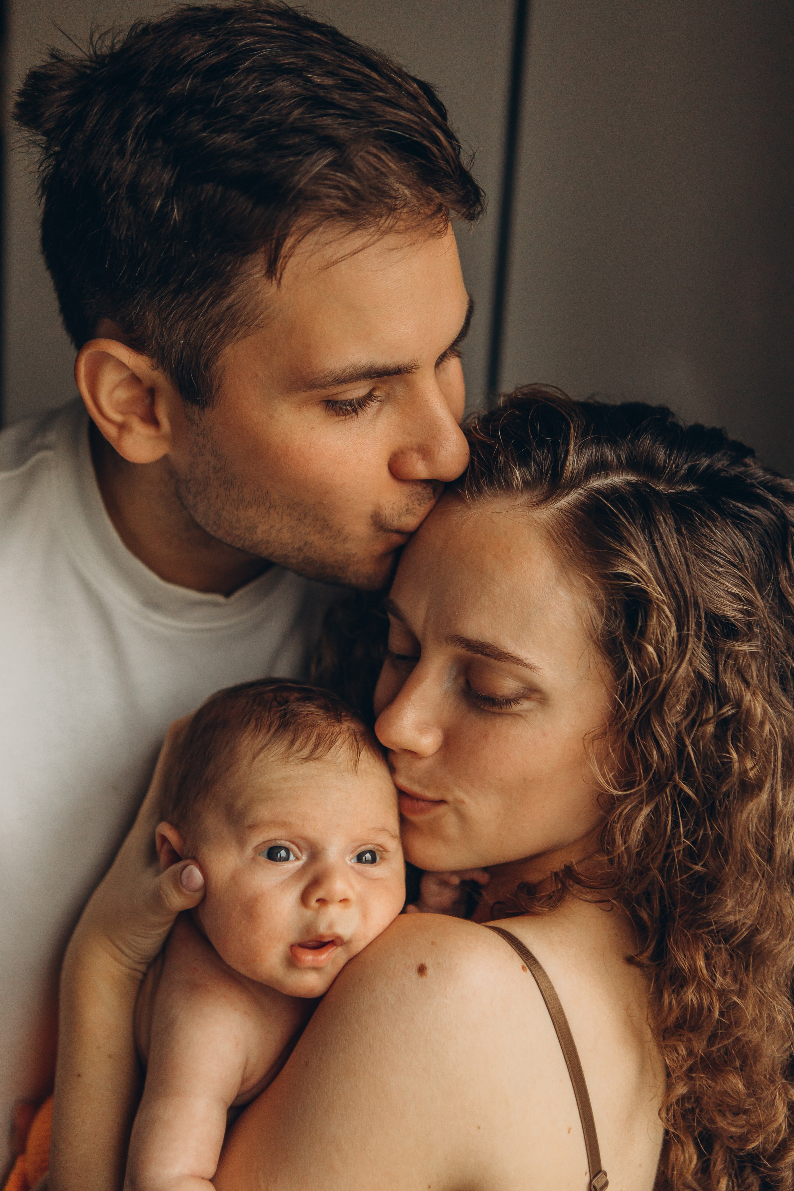 Трепет и любовь в кадре: папа целует маму, а мама — новорожденного малыша. Детский и семейный фотограф в СПб Маруся Самылкина, семейные фотосессии.