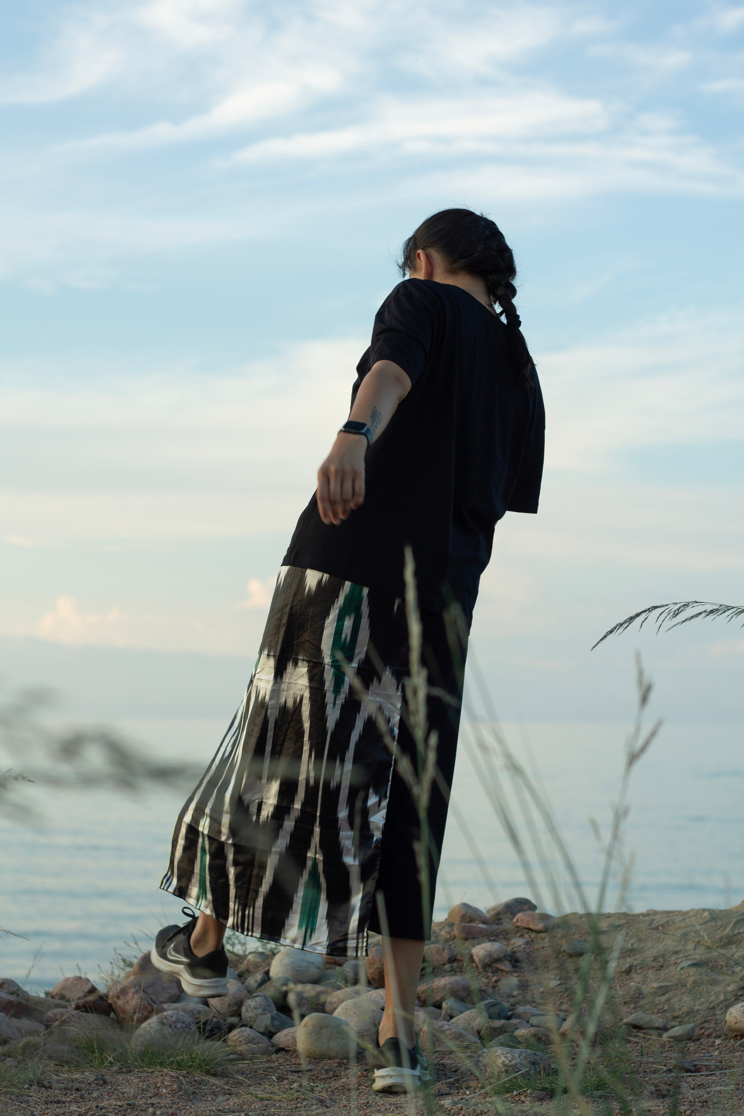 Девушка в национальной одежде стоит на берегу озера 