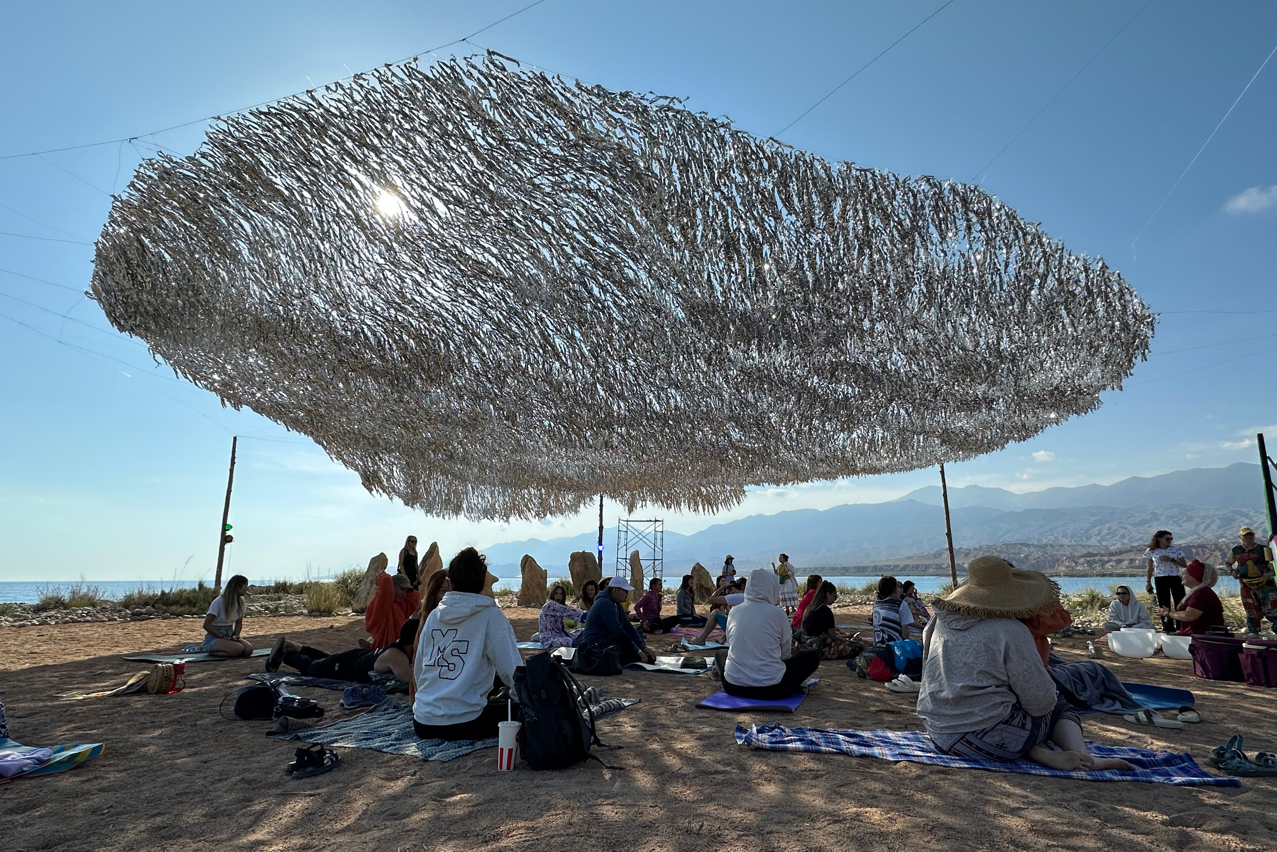 Люди на Көлфест сидят под арт-объектом Чебак днём Кыргызстан 2023 