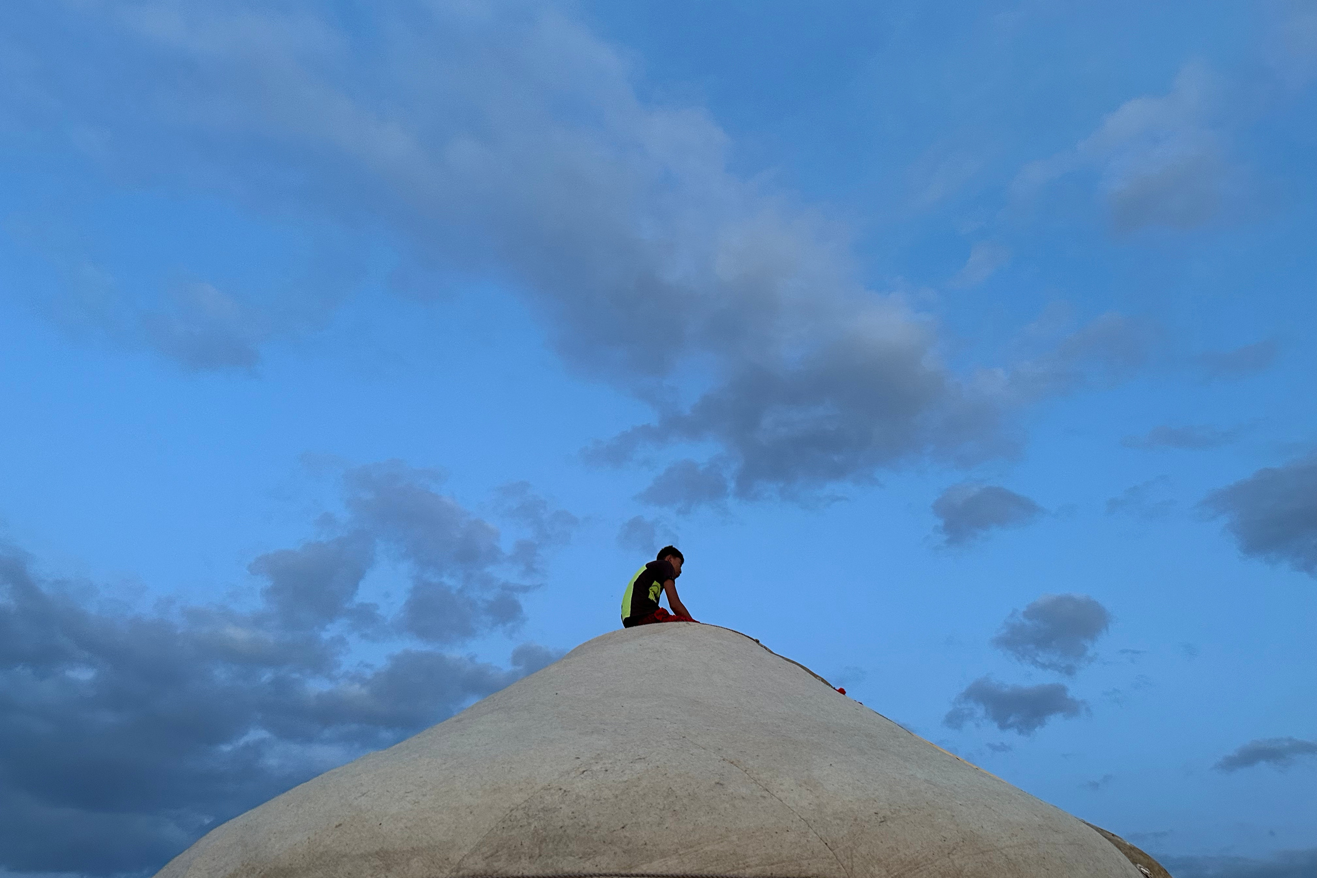 Парень сидит на юрте на Көлфест на закате