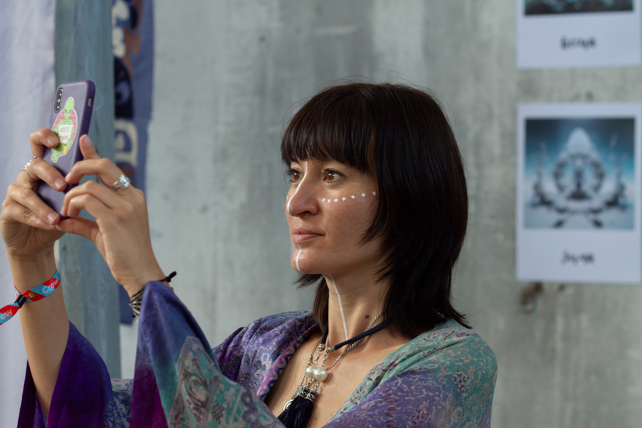 Участница фестиваля Көлфест фотографирует на телефон арт-галерею 