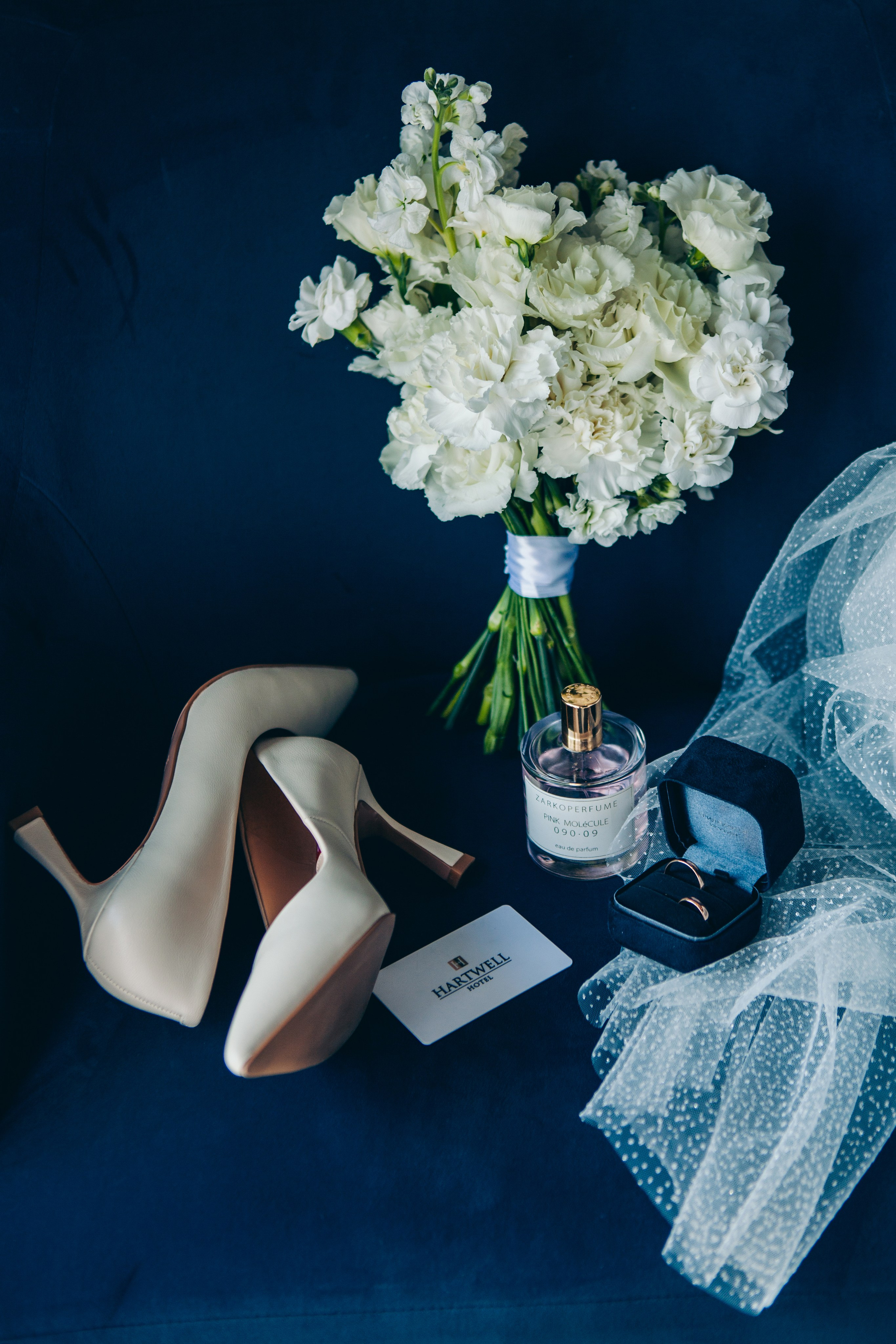 раскладка вещей невесты на синем кресле: туфли, букет, кольца, фата, карточка hartwell