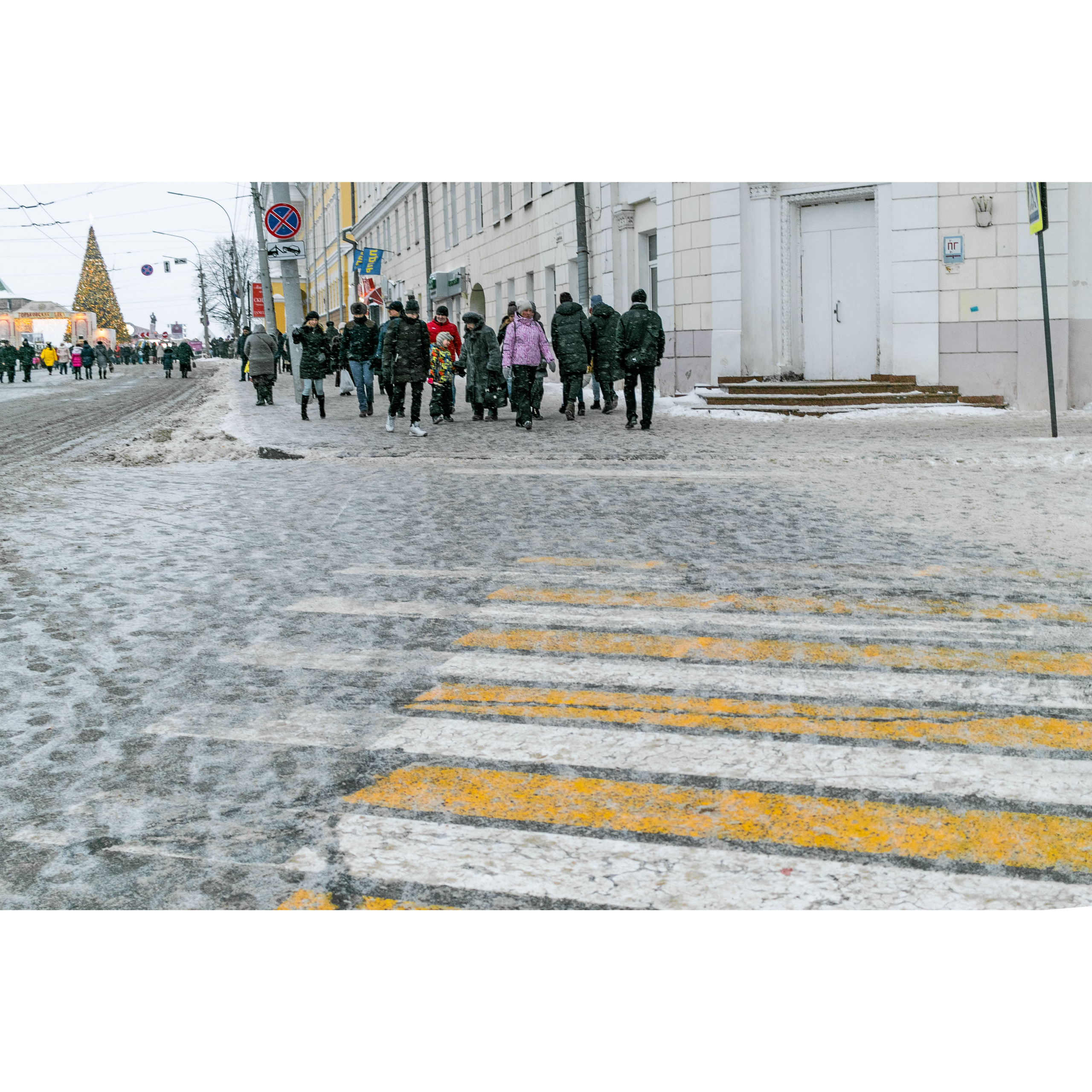 Толпа людей перед пешеходным переходом зимой.