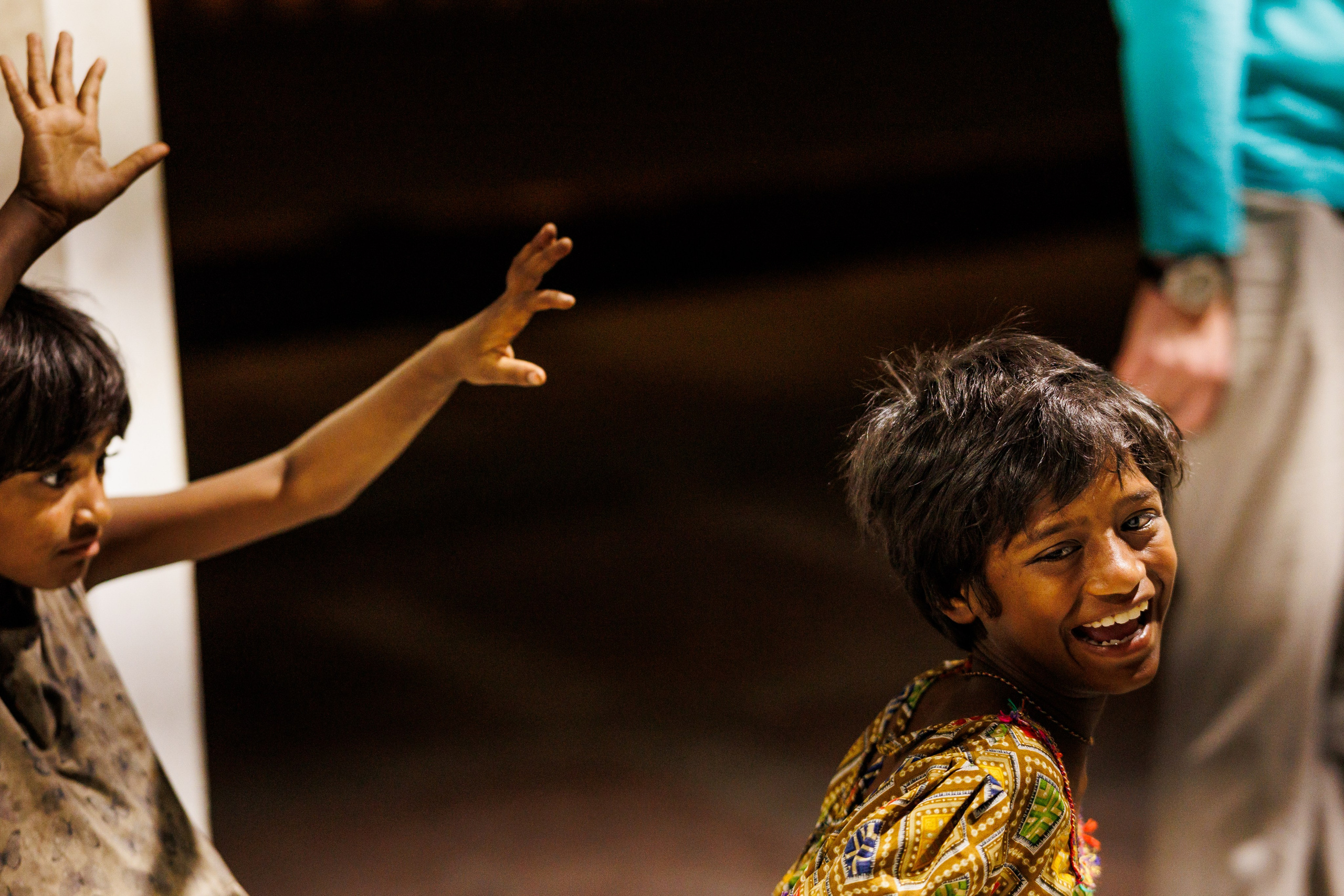 Взрослый человек и ребёнок с тёмной кожей и кудрявыми волосами в полутёмном помещении, взрослый показывает рукой вверх