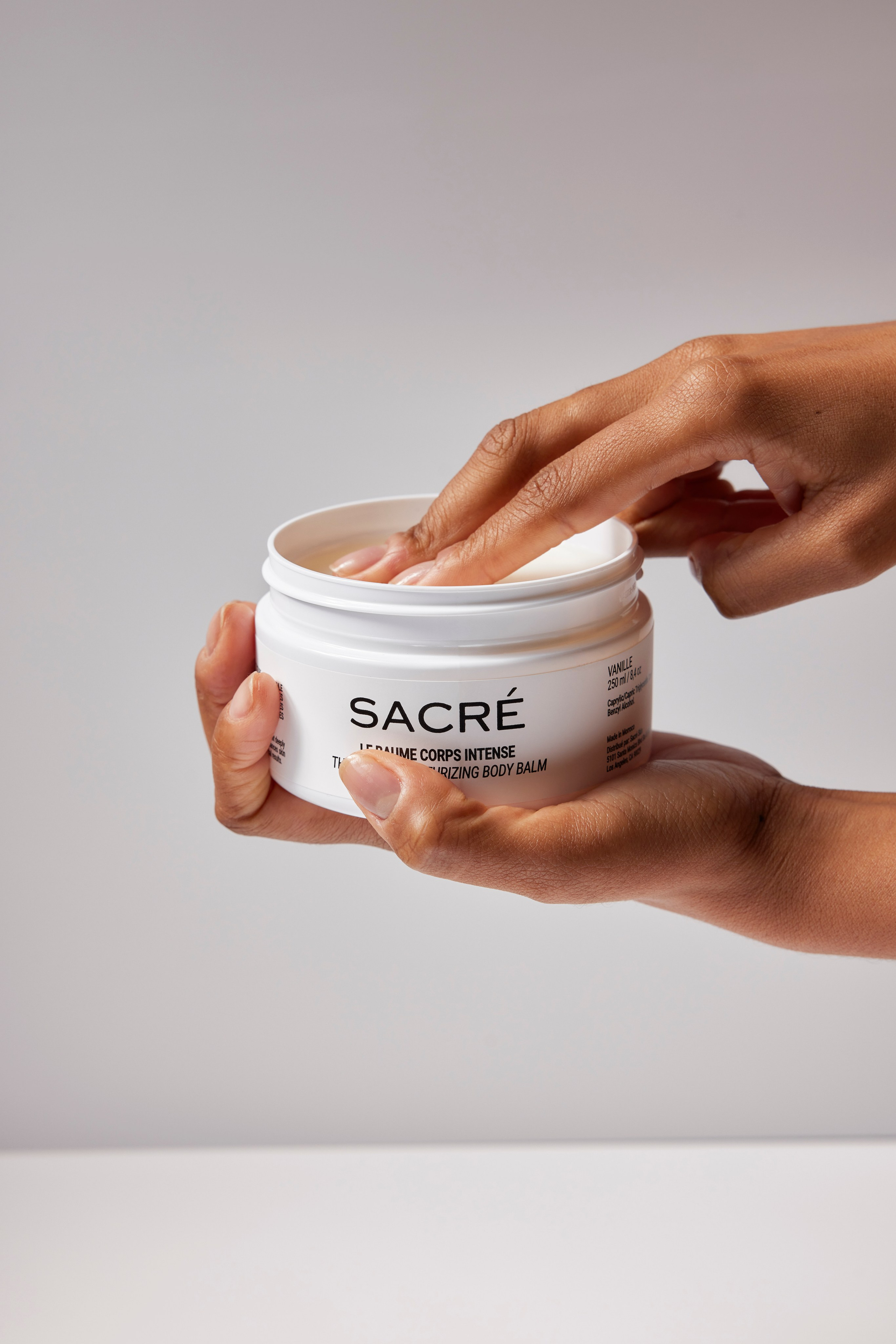 Luxury face cream jar held by a model, representing premium skincare for beauty enthusiasts.