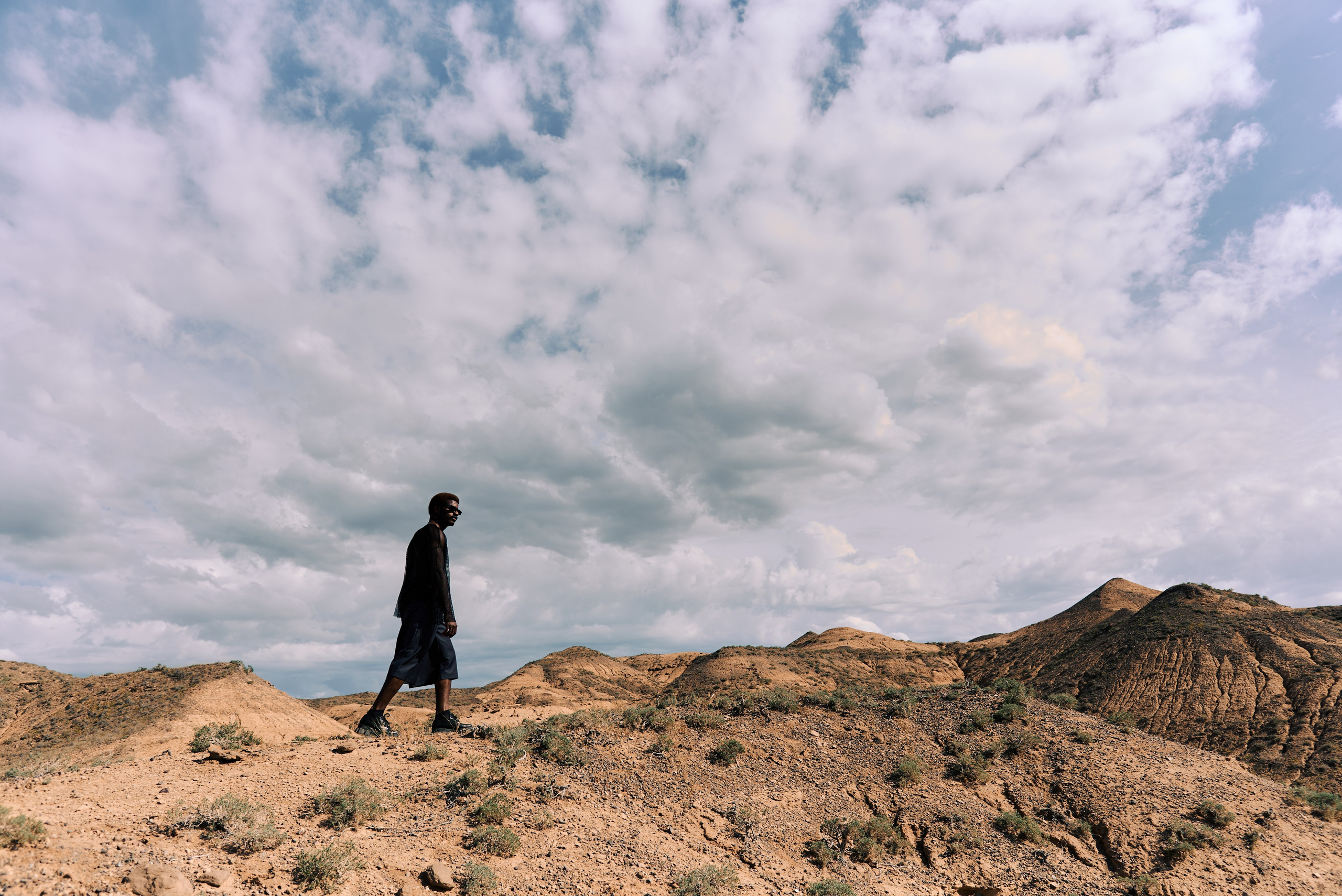 темнокожий мужчина в черном в пустыне общий план