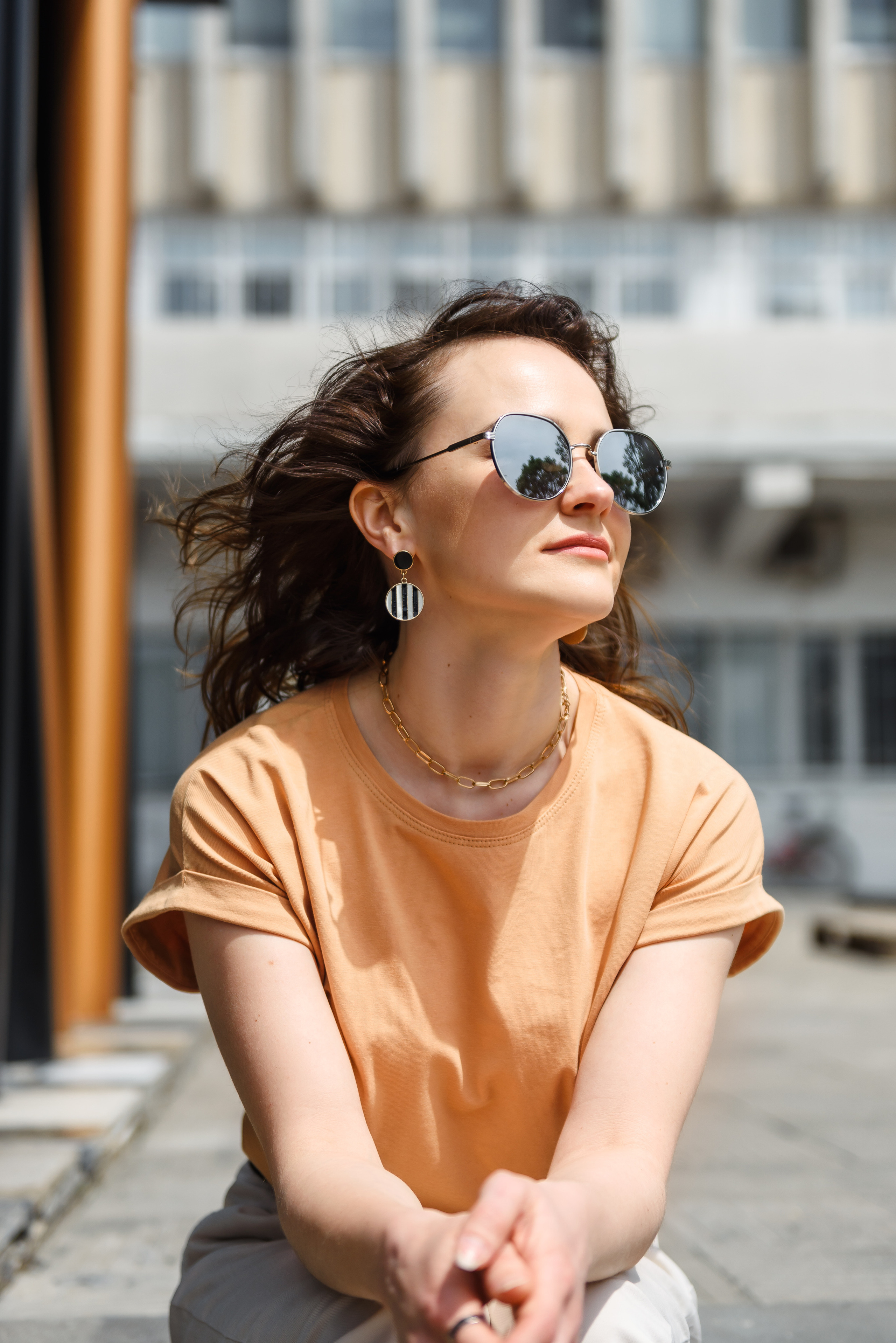 Фотосессия девушки, она сидит в очках, повернув голову к солнцу