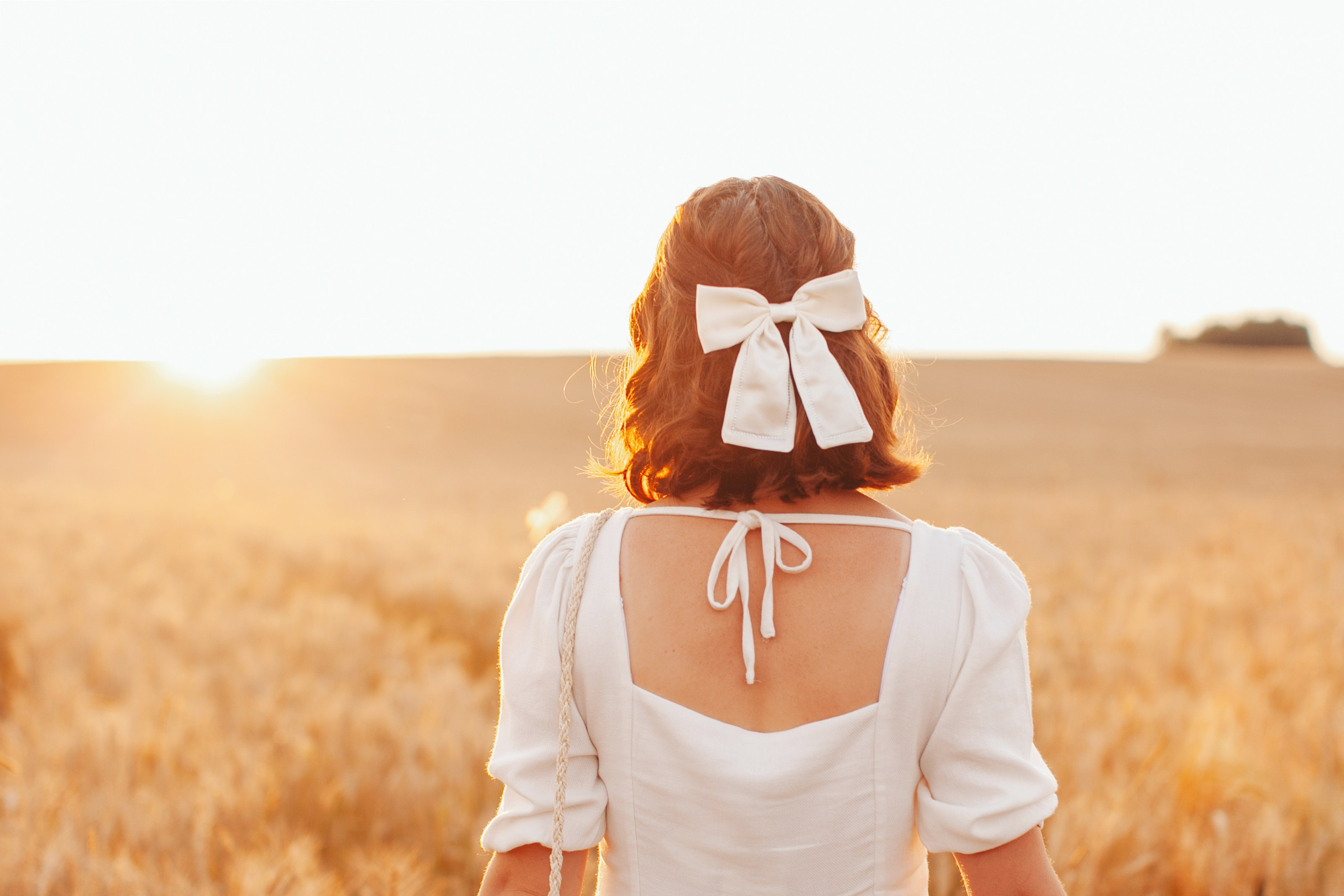 Красивый белый бантик на девушке с коротким каре смотрит на солнце