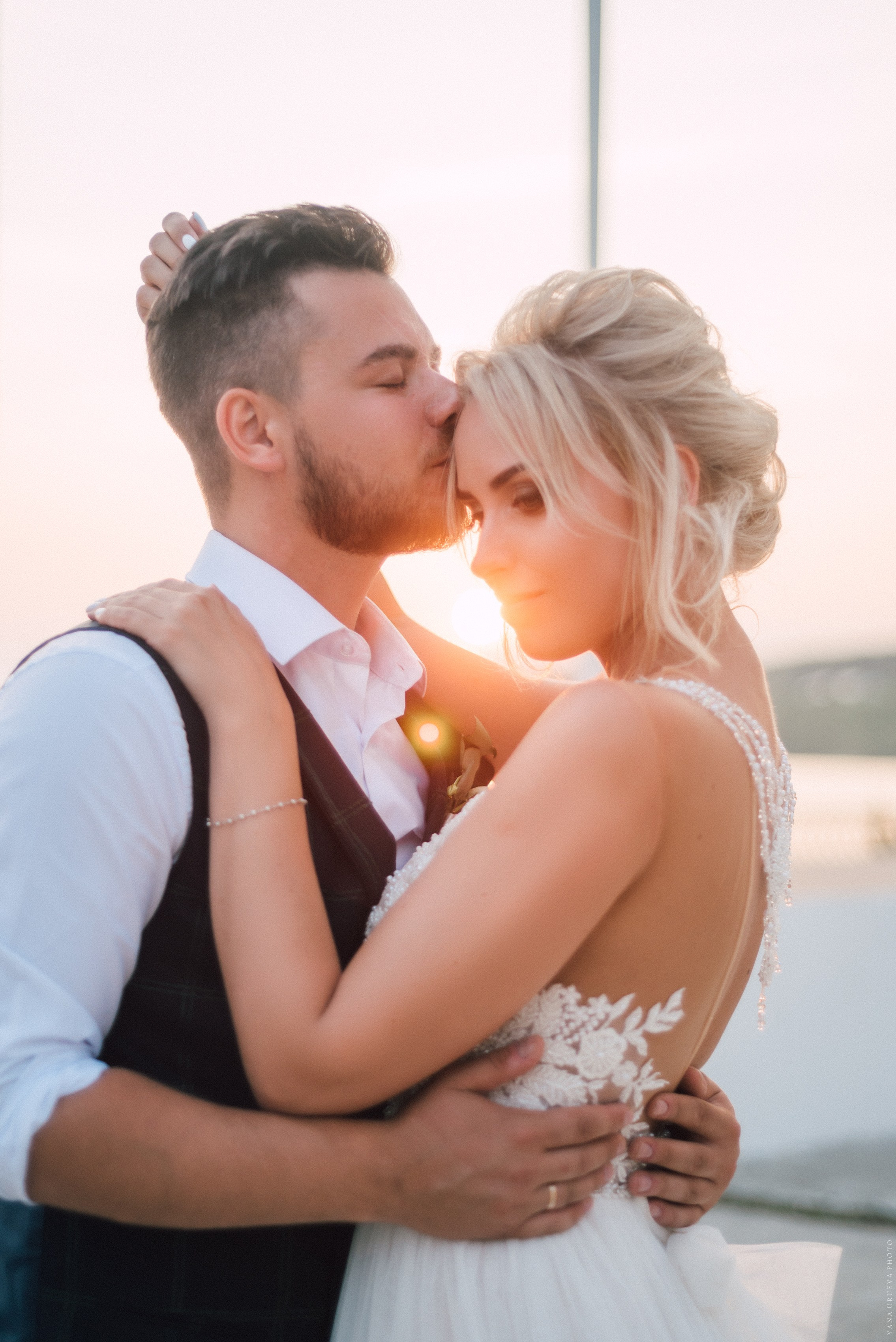 Молодожены целуются на закате на фоне реки