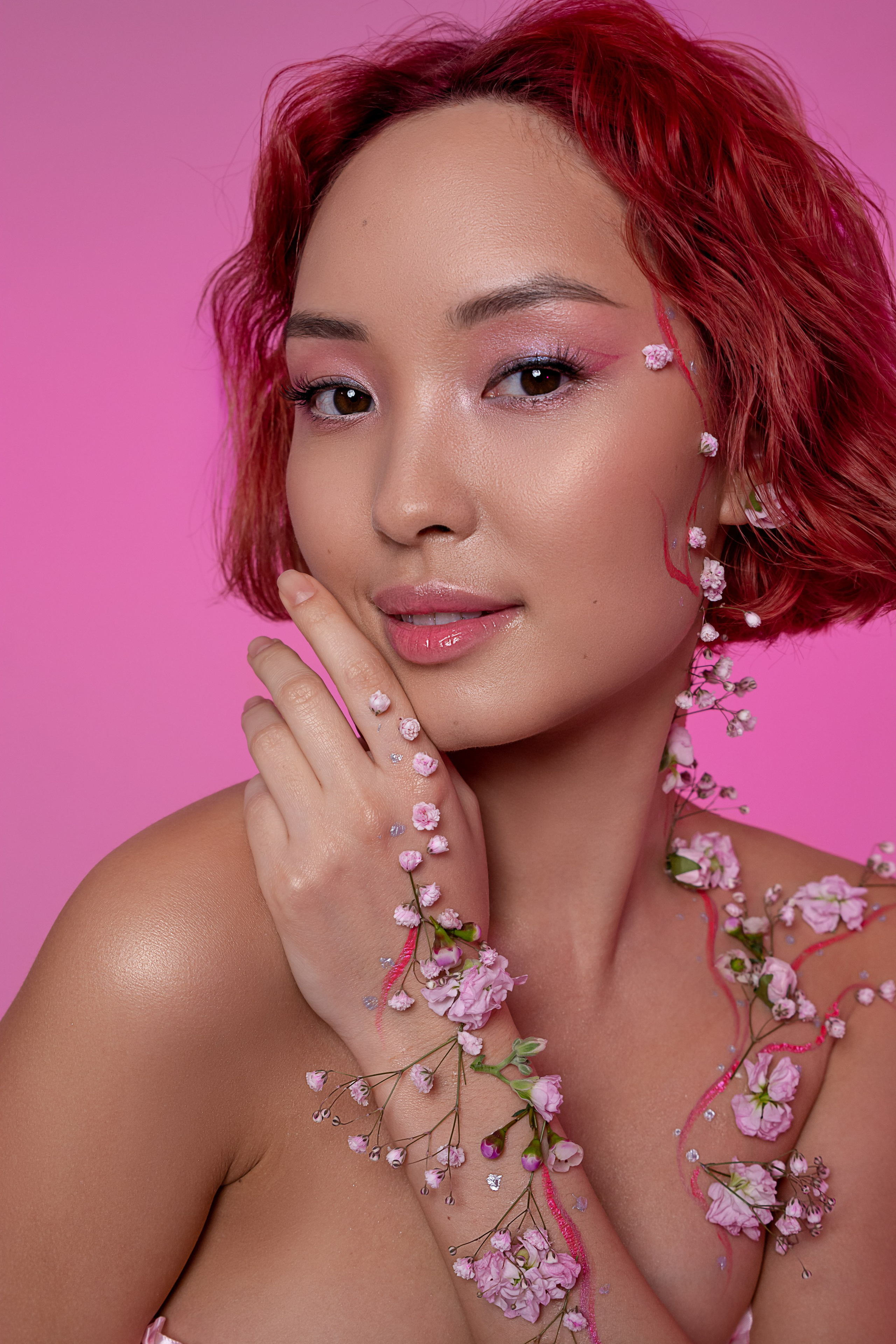 Чувственный портрет девушки из Азии, чья рука и шея украшены живыми цветами, воплощая дух весеннего возрождения.