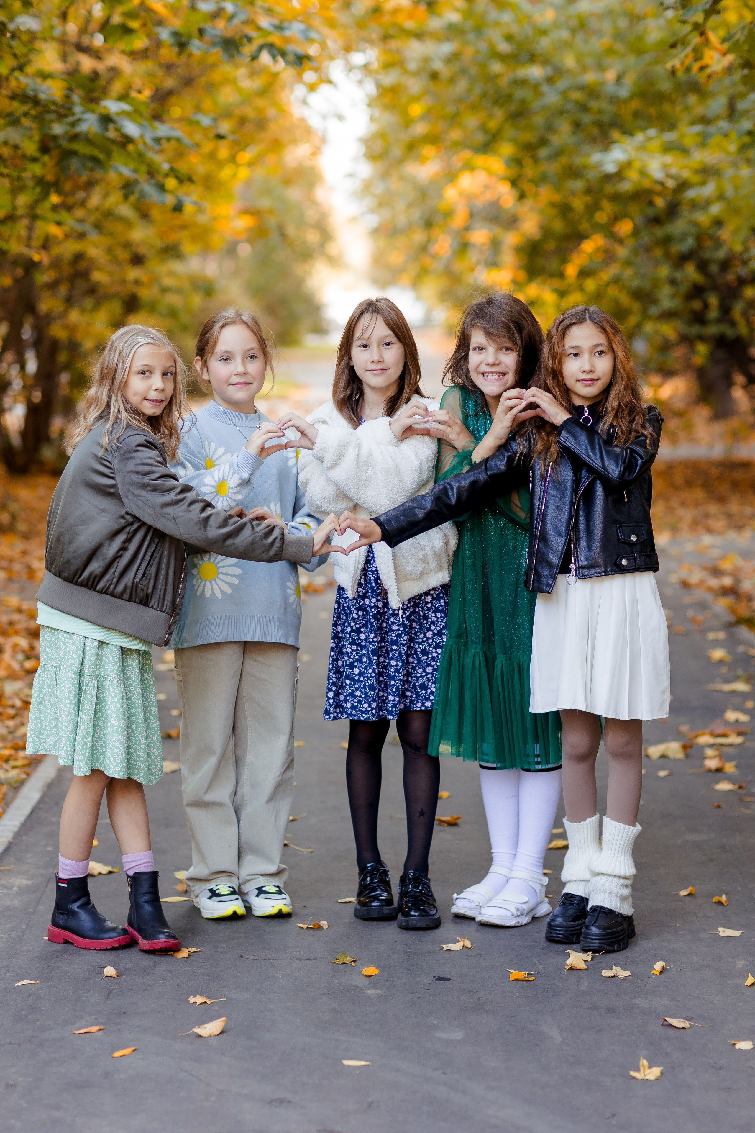 Девочки подружки показывают сердечки в осеннем парке