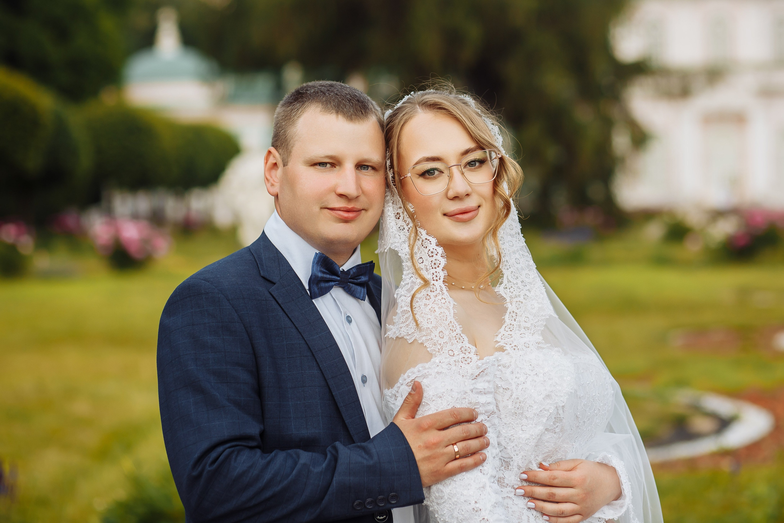 Свадебное фото - молодожёны обнимаются на фоне парка Кусково