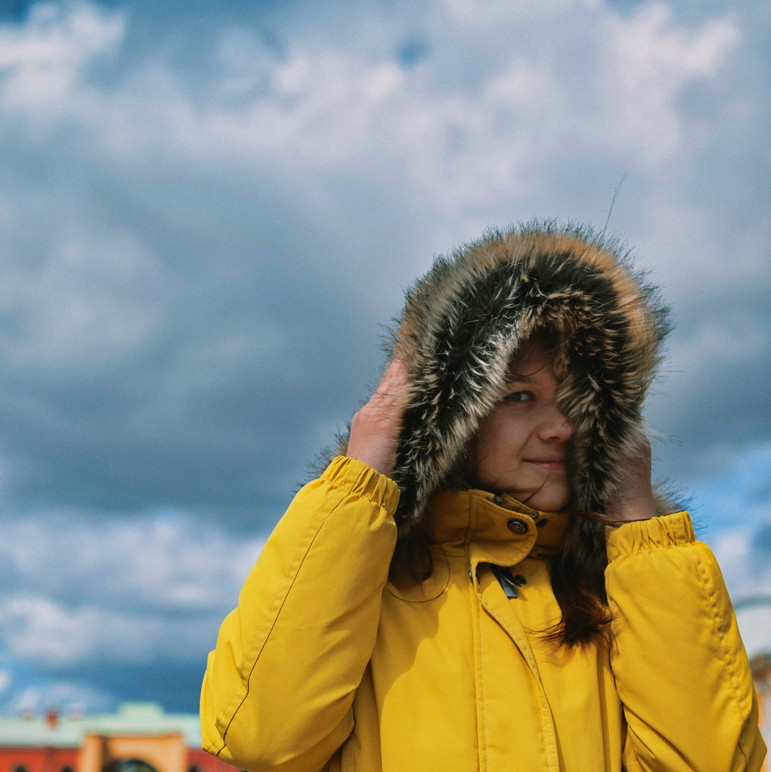 Девочка в желтой куртке на фоне неба