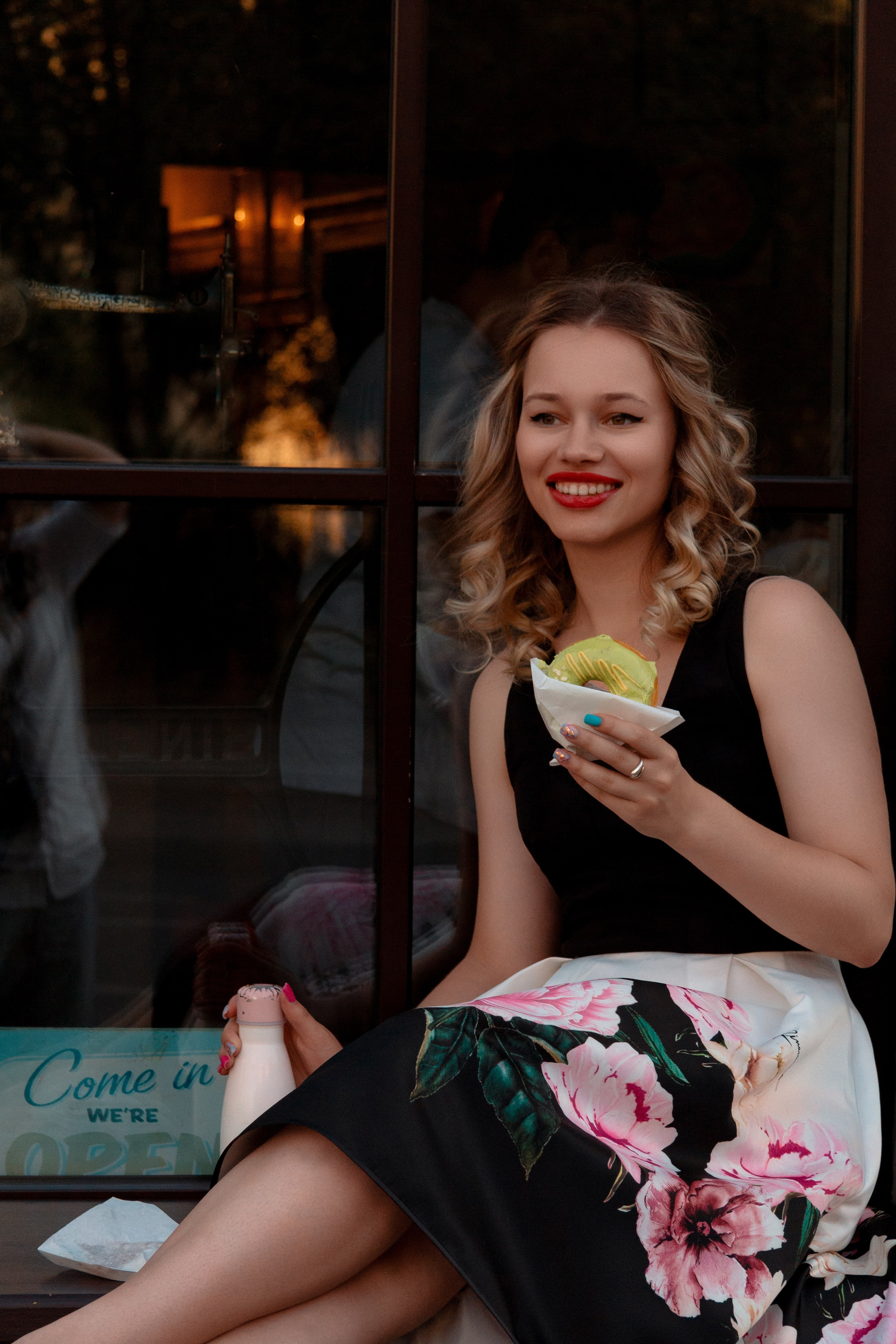 Красивая девушка ест пончики у кафе.