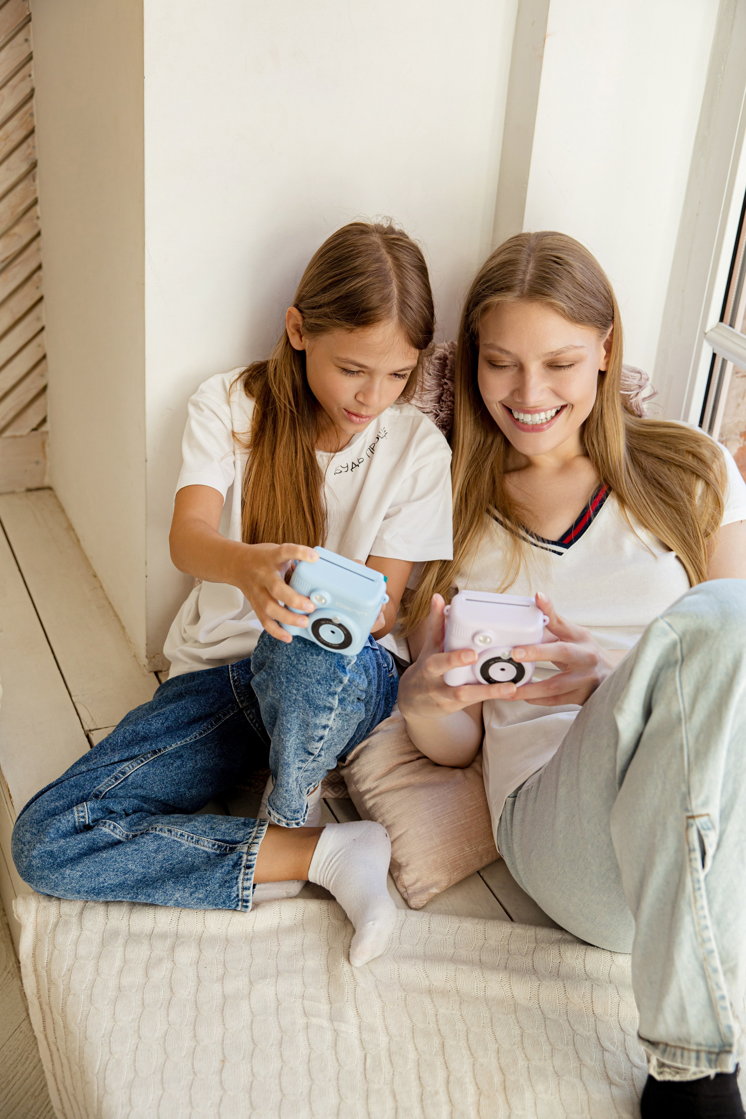 Две сестры с камерами моментальной печати в руках у окна