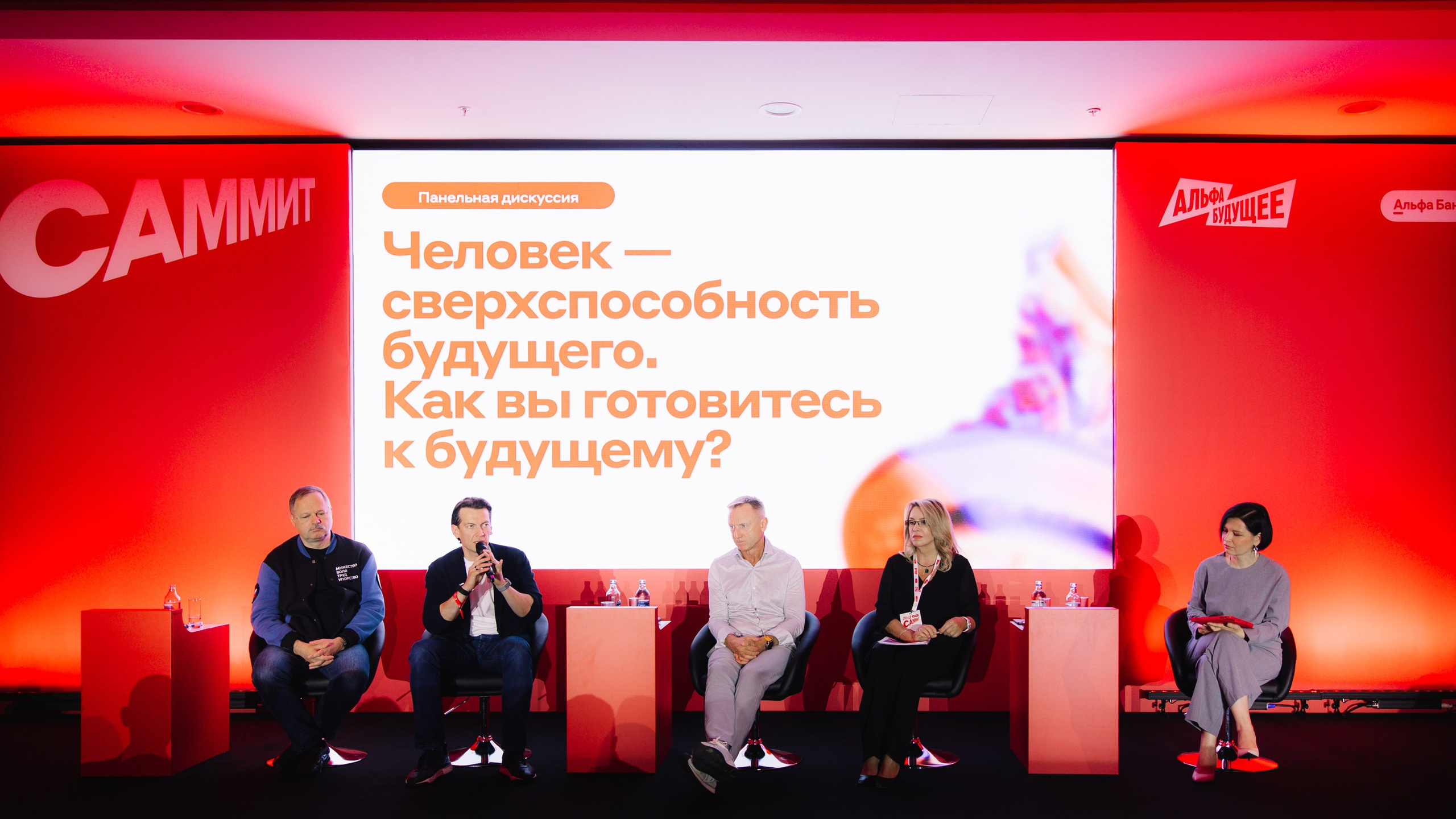 Панельная дискуссия: Четыре спикера на сцене во время обсуждения темы будущего и сверхспособностей человека.