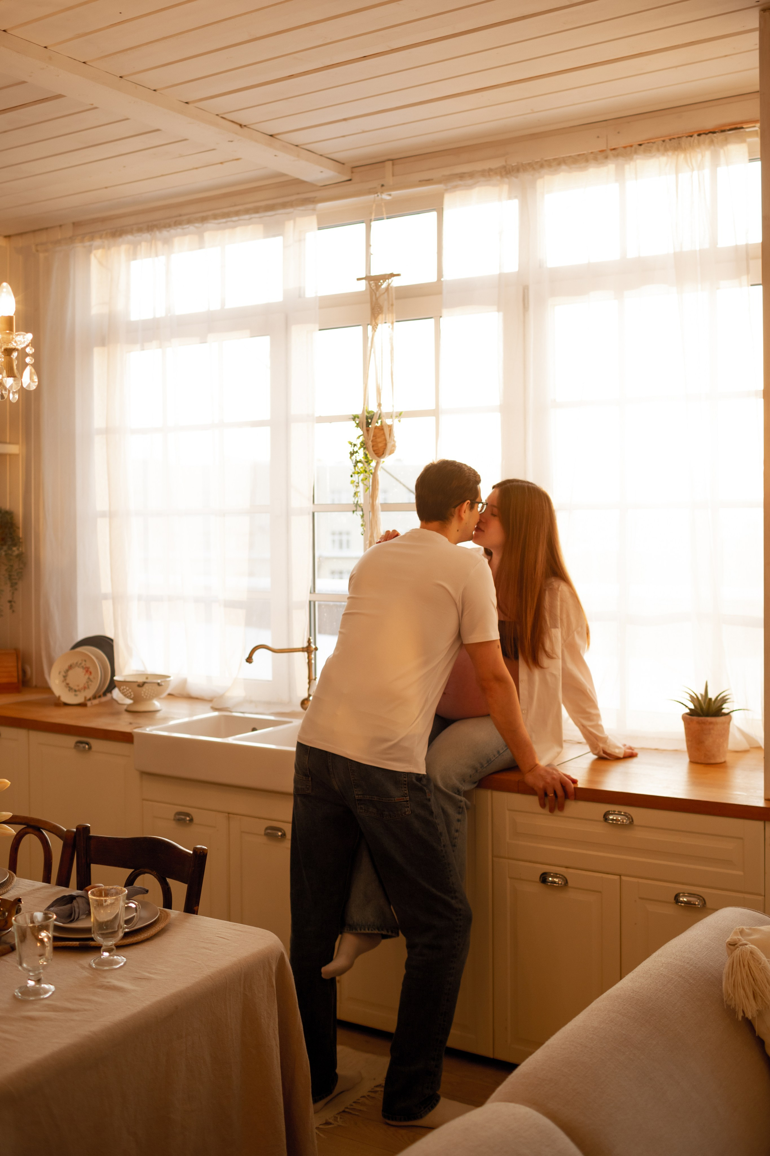 Молодая беременная семья смеется на кухне