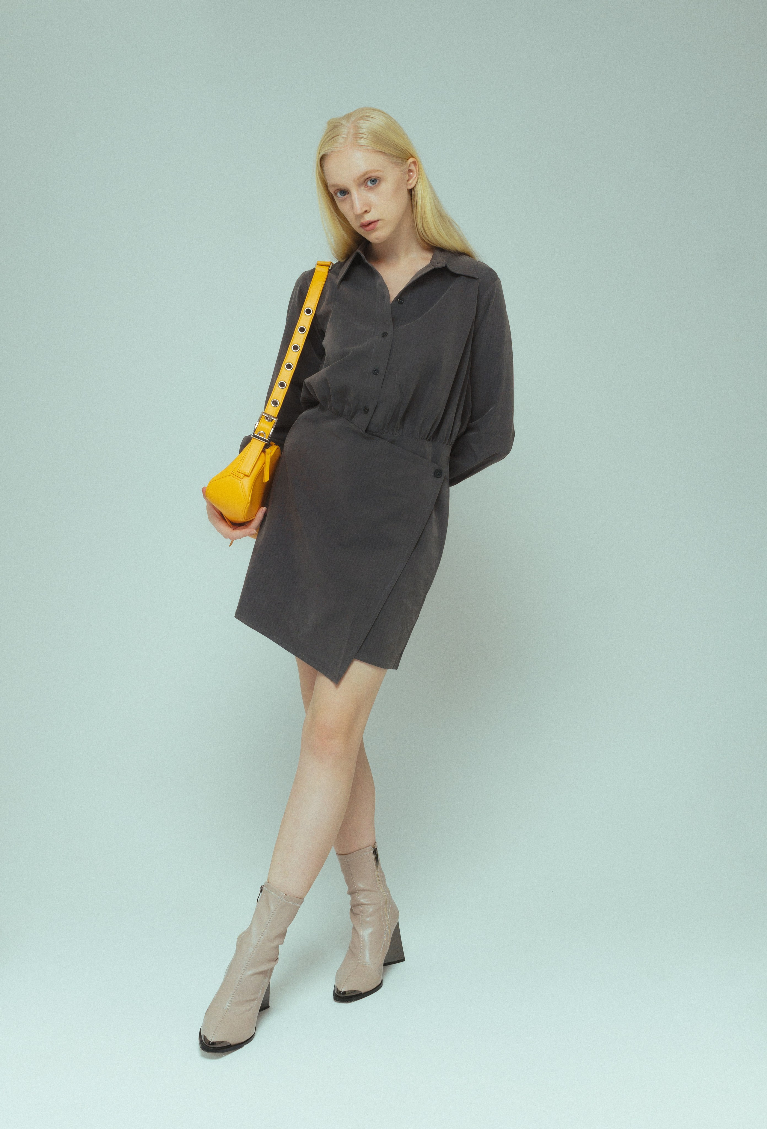 Девушка модель блондинка в сером платье с желтой сумкой на плече