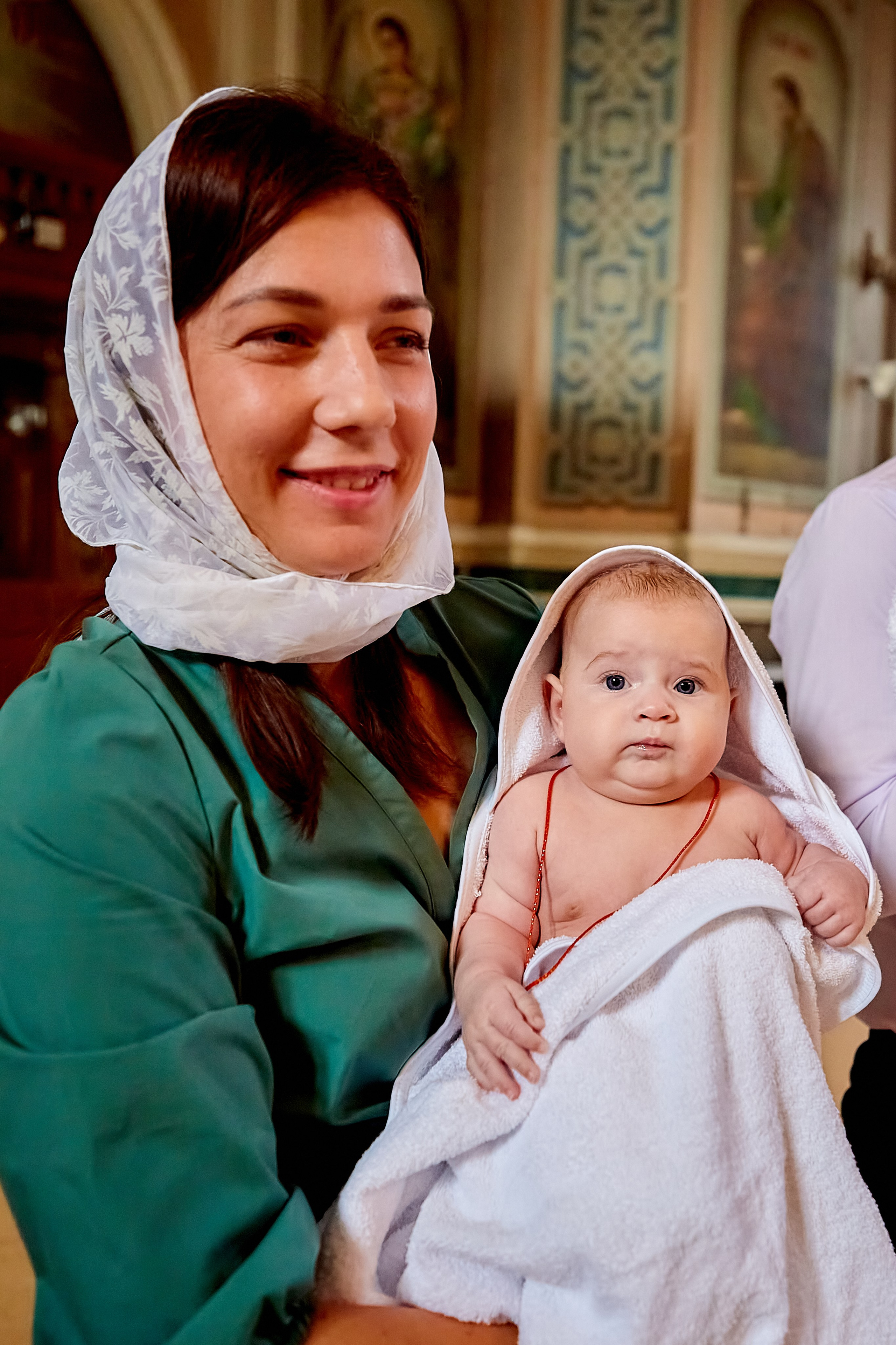 Радость мамы с малышкой на руках на крещении