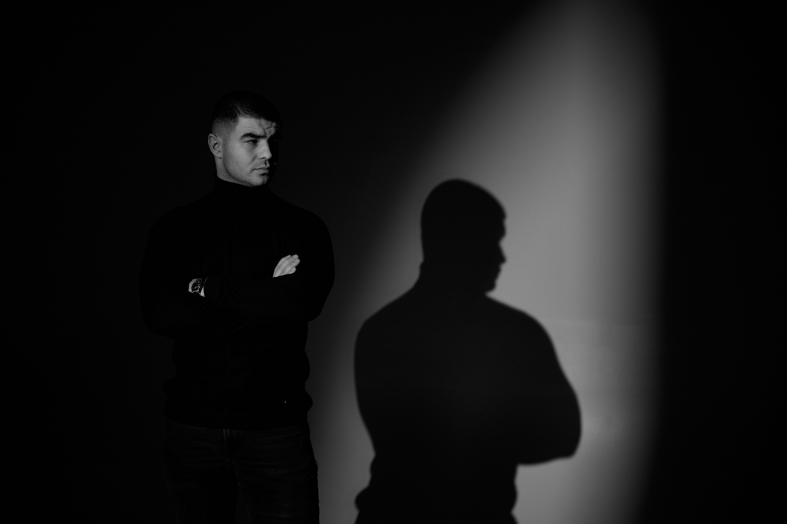 Мужчина на фоне стены, на которую падает тень