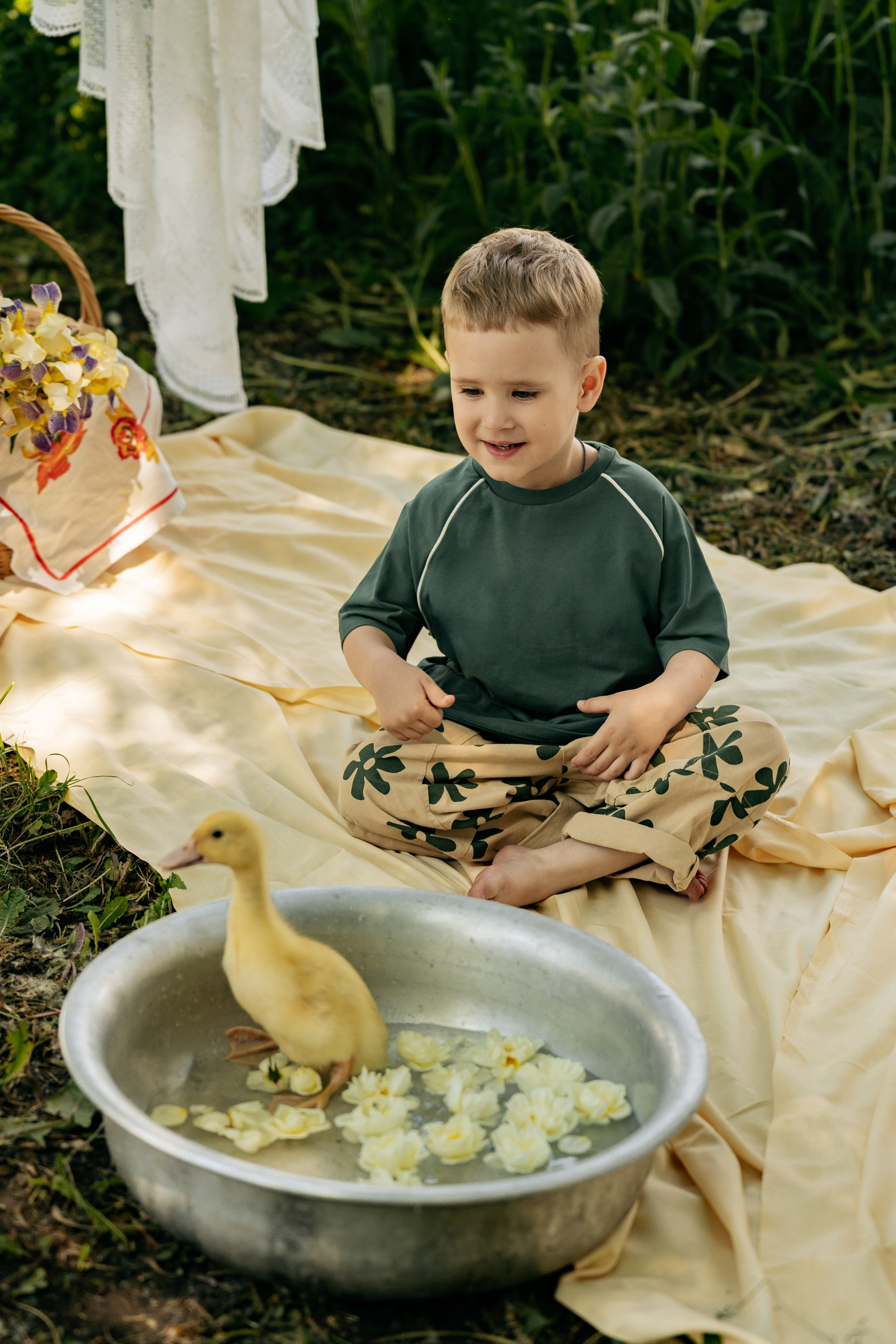 Счастливая семья на природе: малыш с интересом разглядывает утят в тазике, мама поддерживает его, фотограф Геленджик