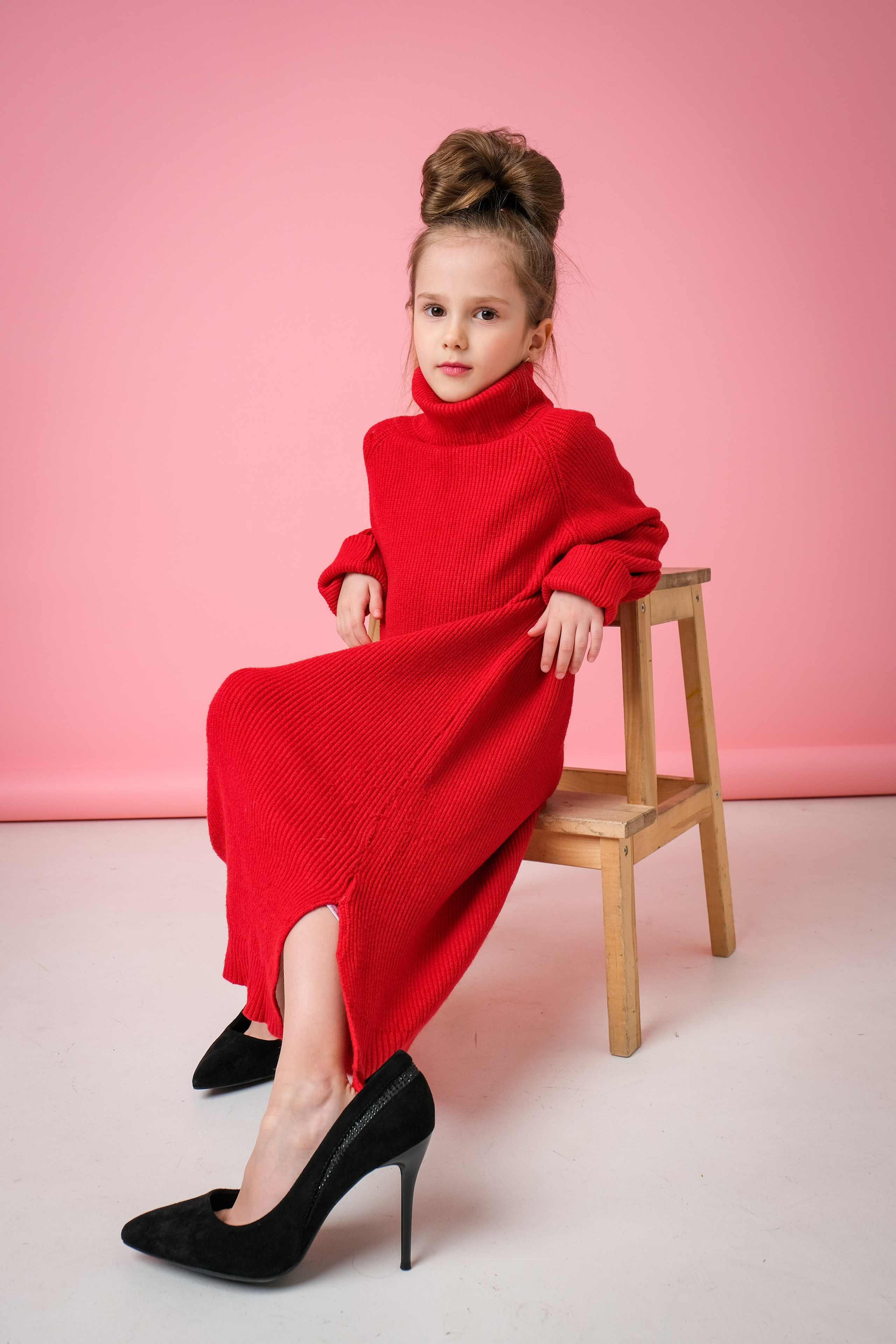 Девочка в маминой одежде сидит на стуле