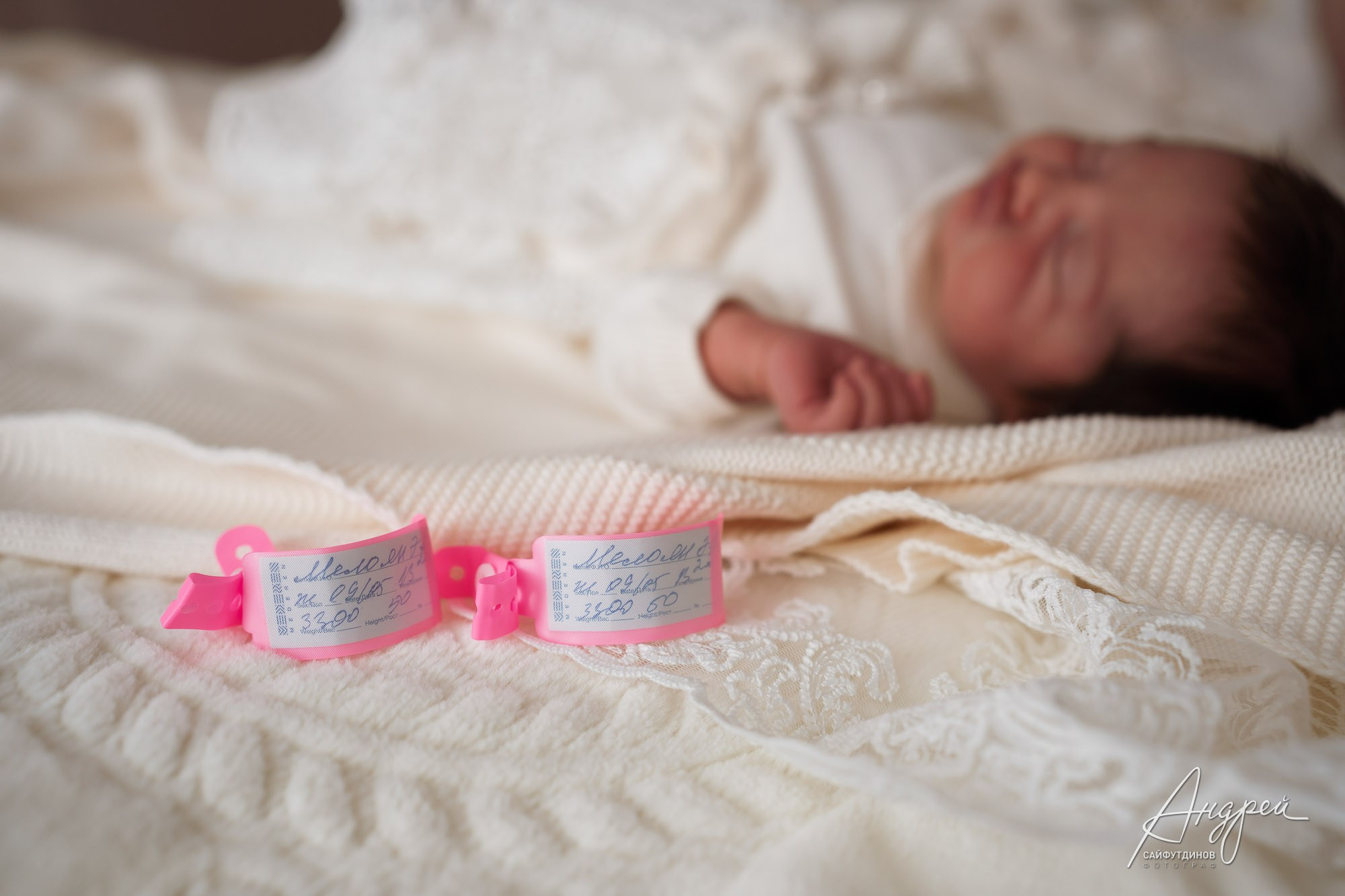 Бирки новорожденной на фоне спящей девочки, фотосъемка первых дней жизни ребенка в Ростове-на-Дону.