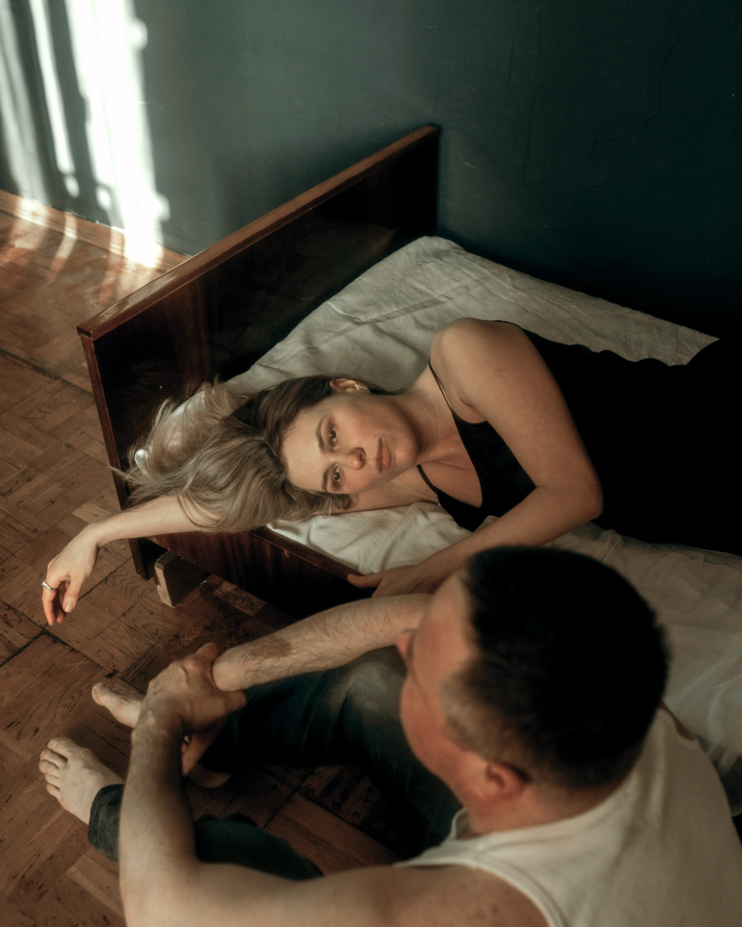 Арт фотосессия пары в спальне, девушка лежит на кровати и смотрит в кадр в винтажном интерьере, чувственная съемка пары в темной арт стилистике с эффектом погружения в историю