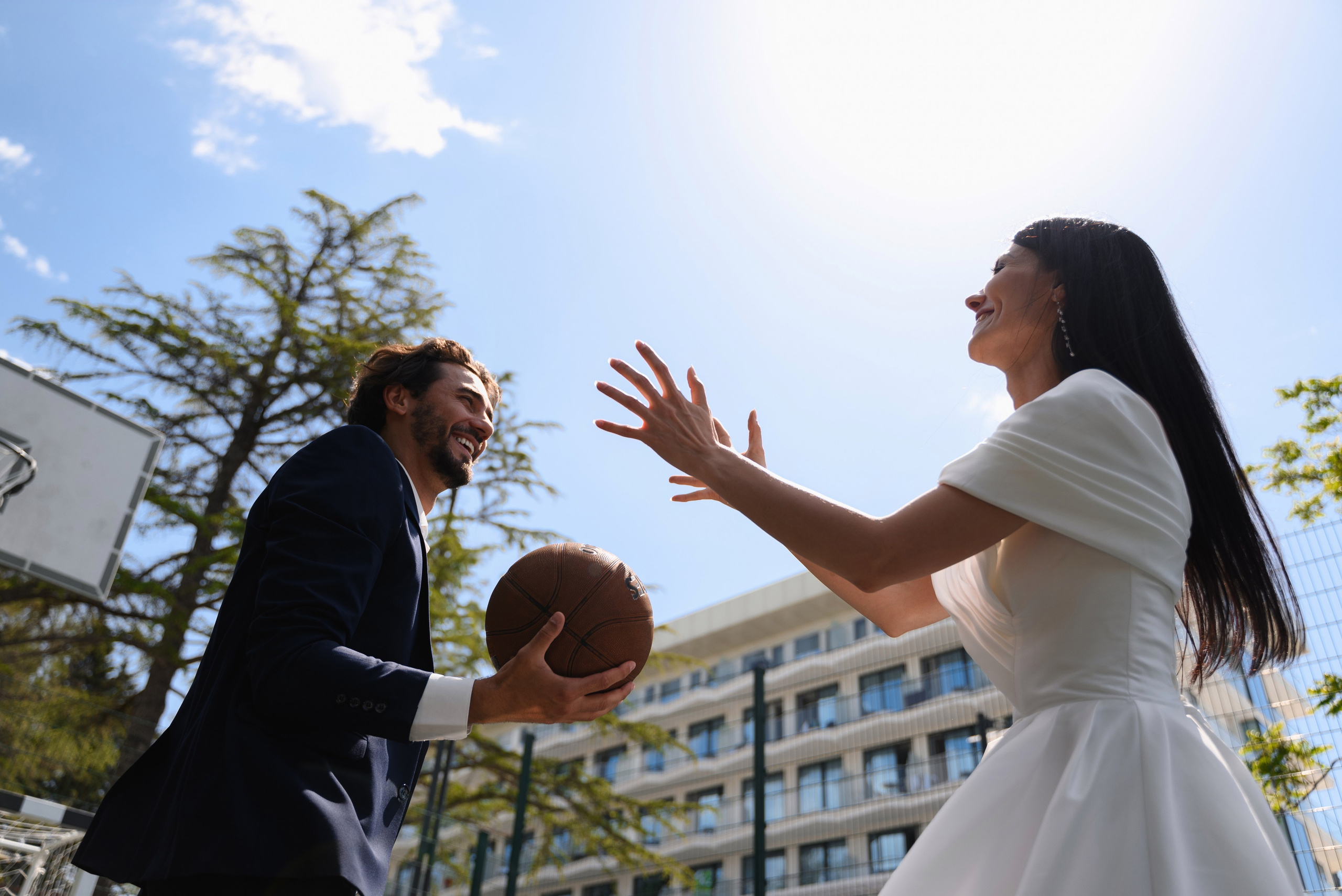 Вдохновляющие свадебные фотографии на фоне зелени и чистого неба Сочи где жених подбрасывает вверх баскетбольный мяч 