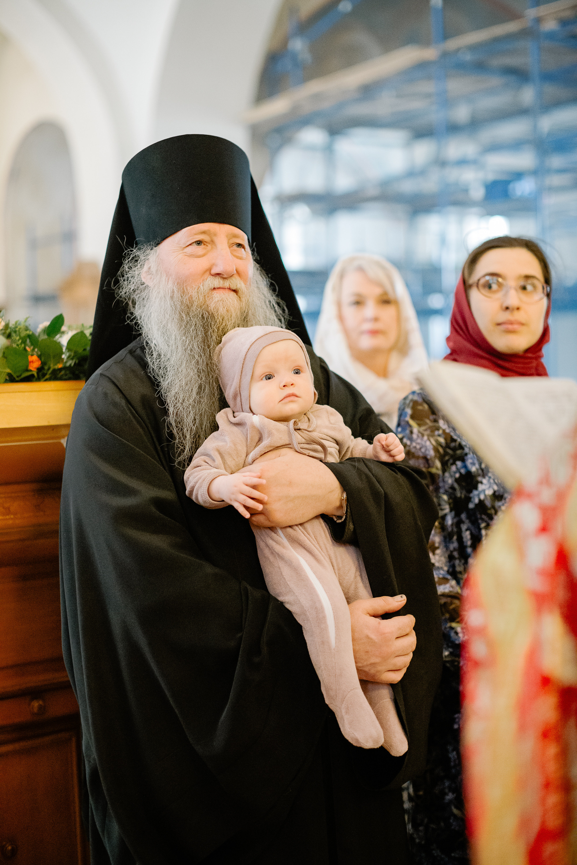 Монах держит на руках младенца, которого крестят. 