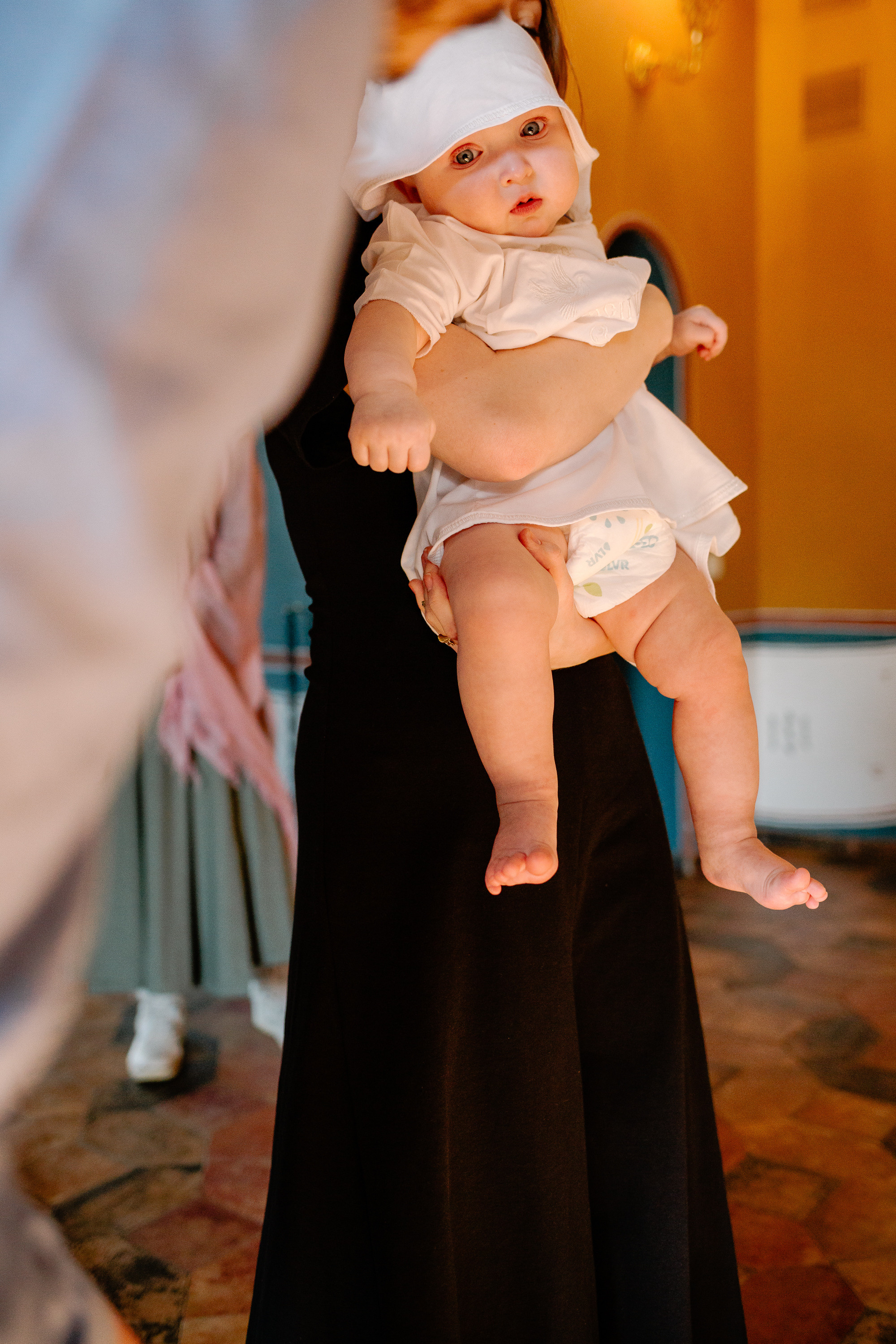 Крестят малыша, младенец на руках у крестной.