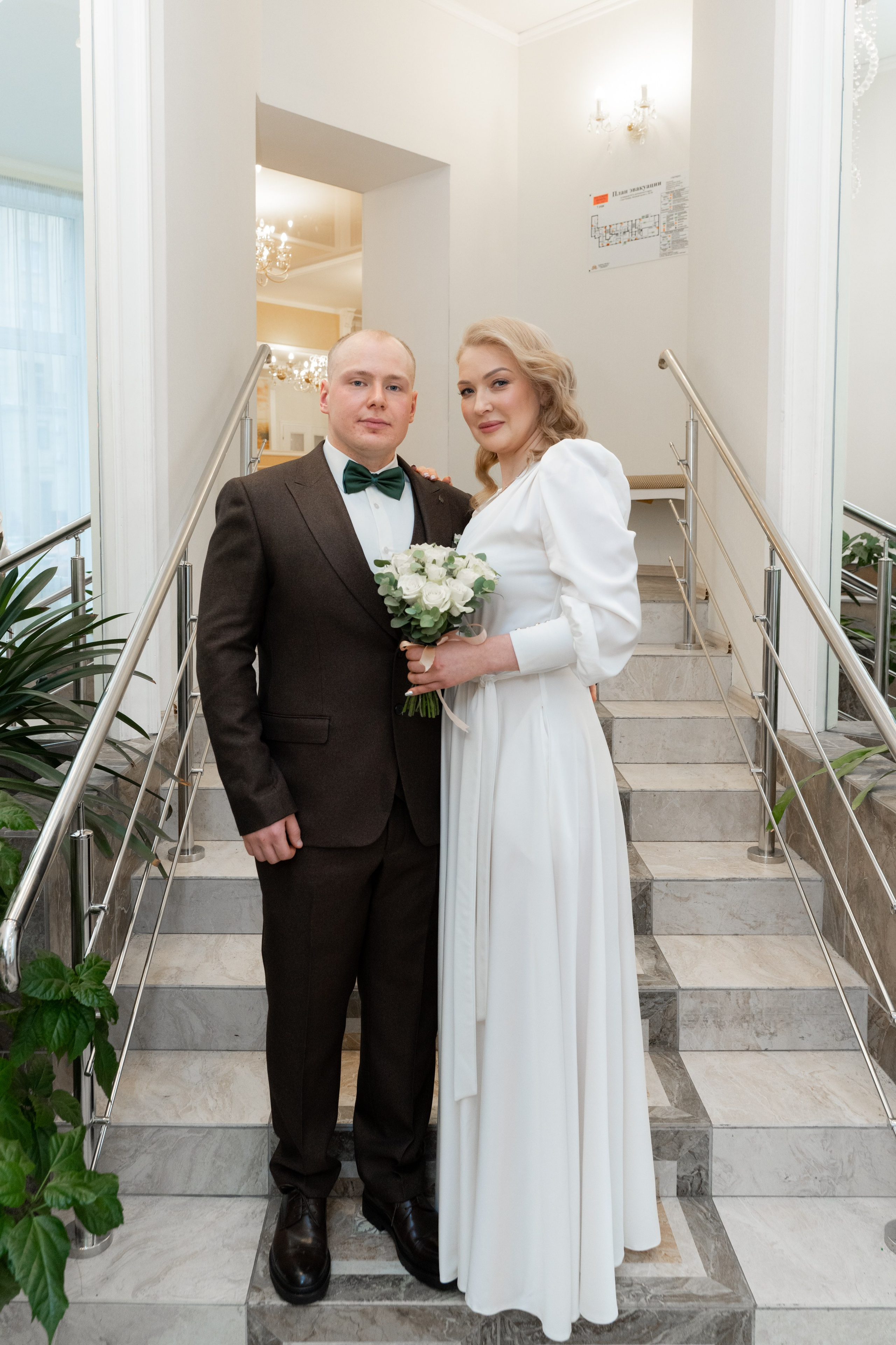 жених и невеста стоят на лестнице в загсе московского района
