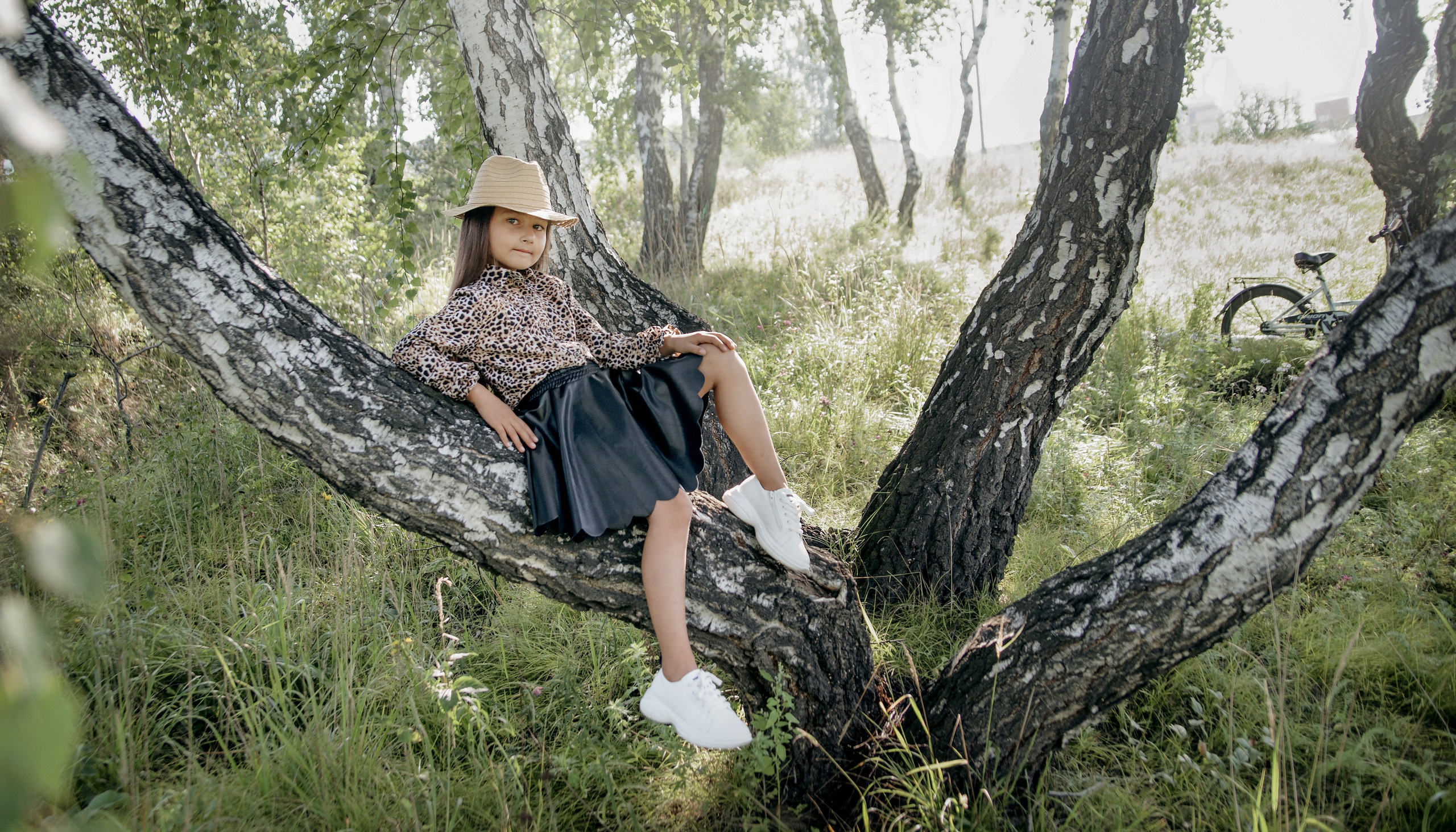 Детская фотосессия летом - девочка сидя на дереве