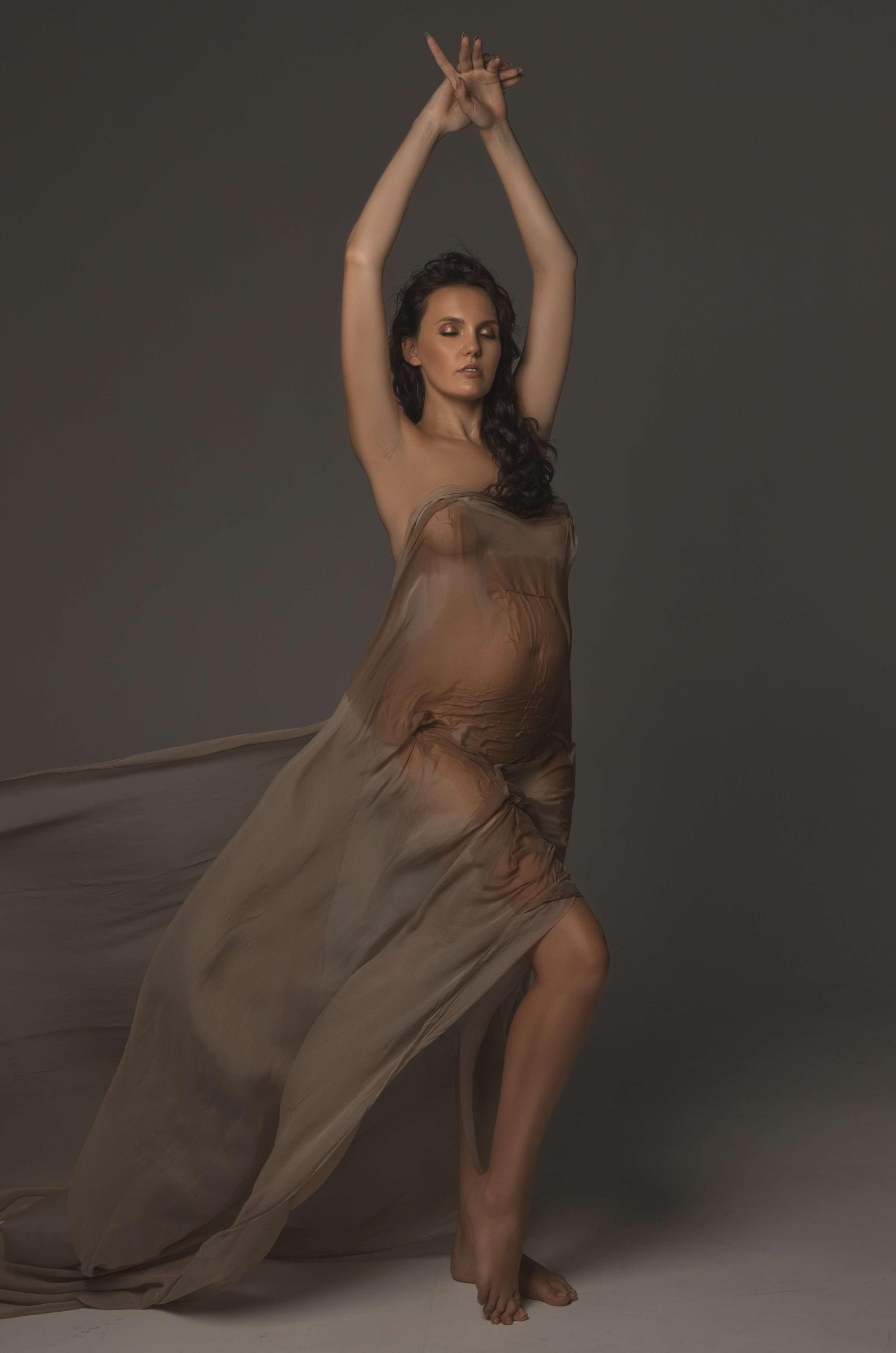 фотосессия беременной в фотостудии на темном фоне в красивом разлетающемся платье, фотография беременности, фотосессия беременных, портрет беременной