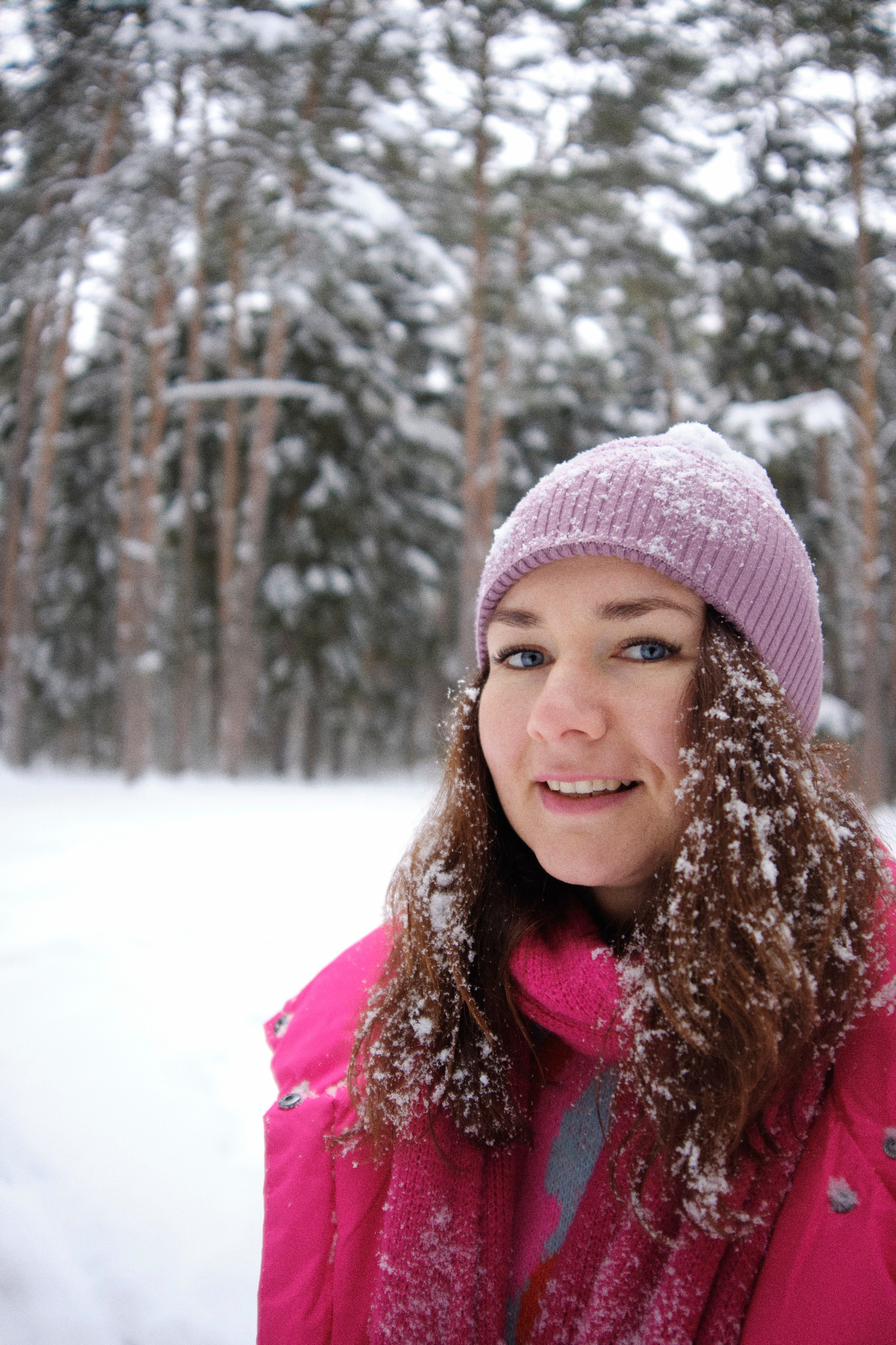 Женщина в зимнем лесу со снежинками на волосах