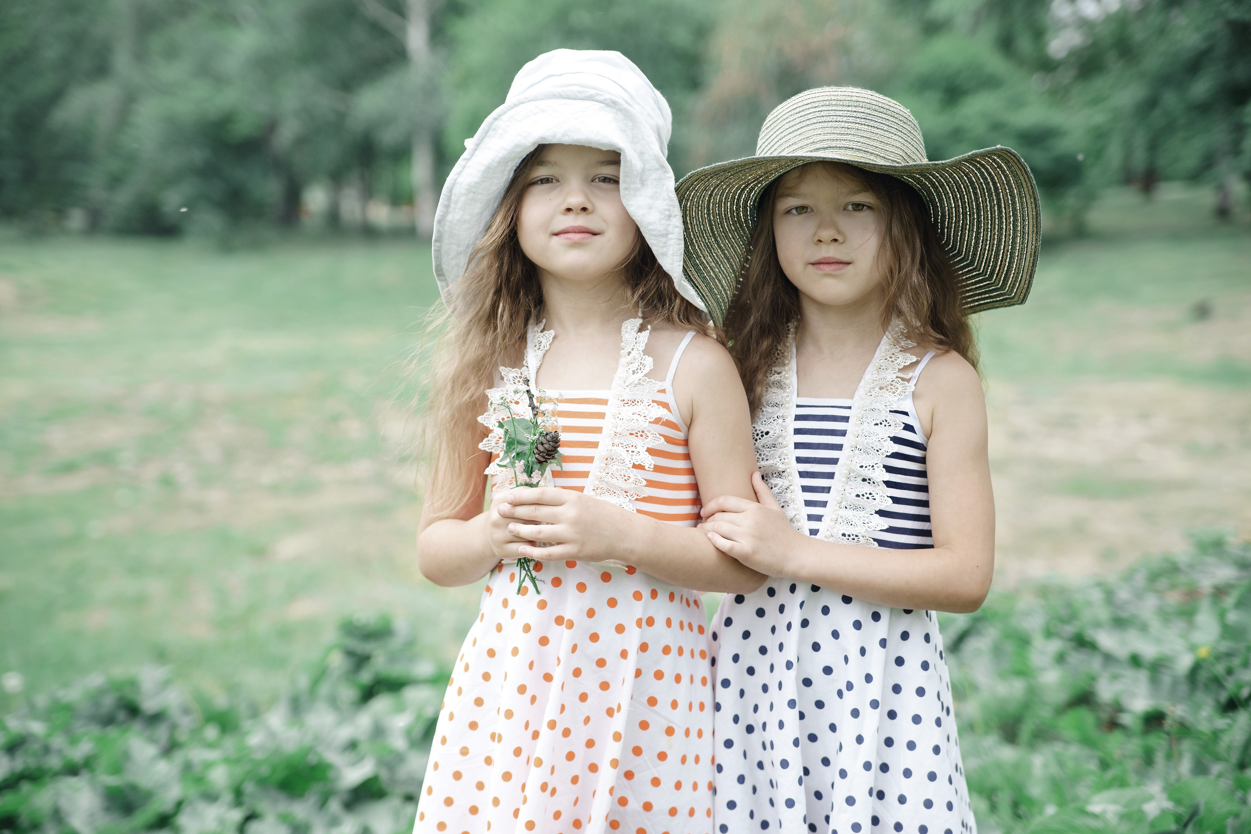 Детская фотосессия летом - сестры стоя смотрят в камеру