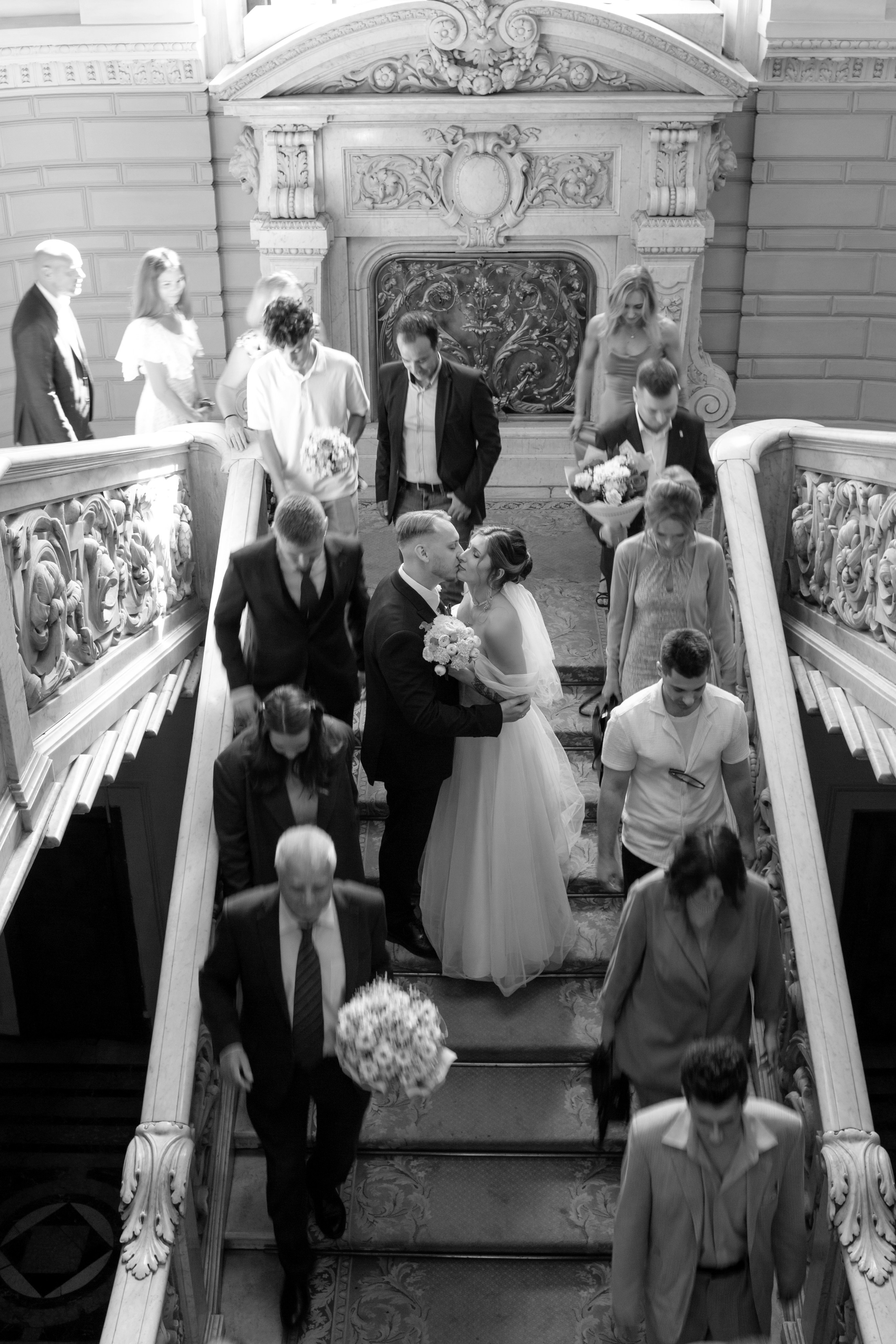 Идея для красивой фотографии: жених и невеста целуются на парадной лестнице Дворца бракосочетания №1, а гости пробегают мимо.