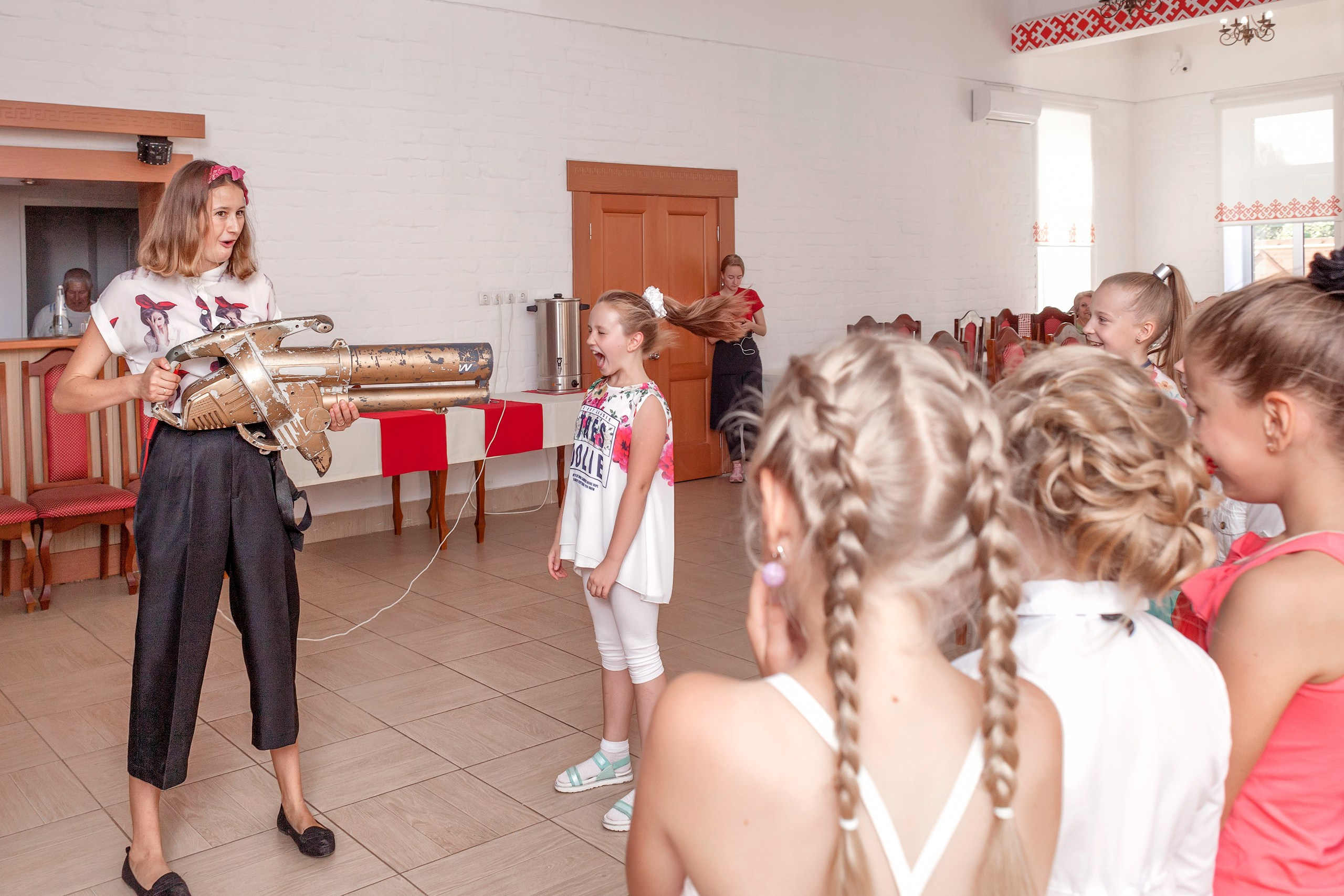 Аниматор показывает детям работу прибора на детском празднике