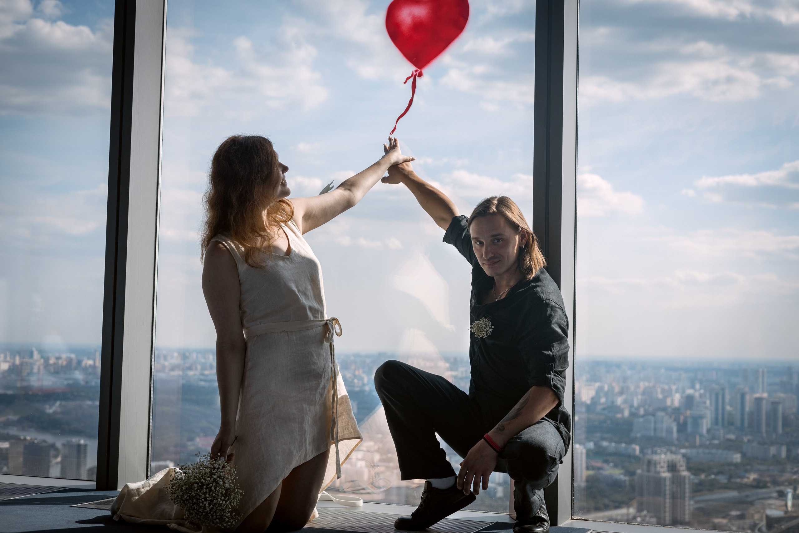 свадебная фотосессия муж и жена сидят и держат воздушный шарик