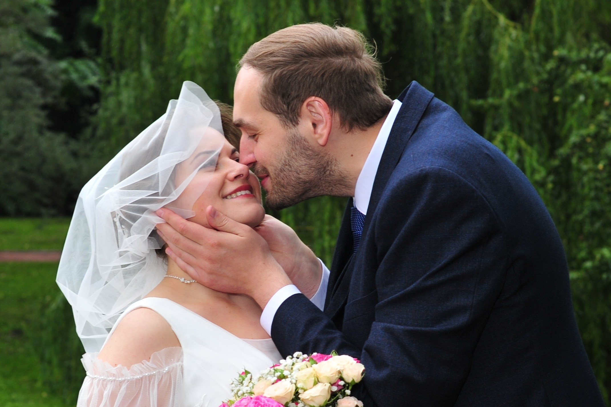 Свадьба в Царицыно пасмурным летним днем, жених нежно целует невесту