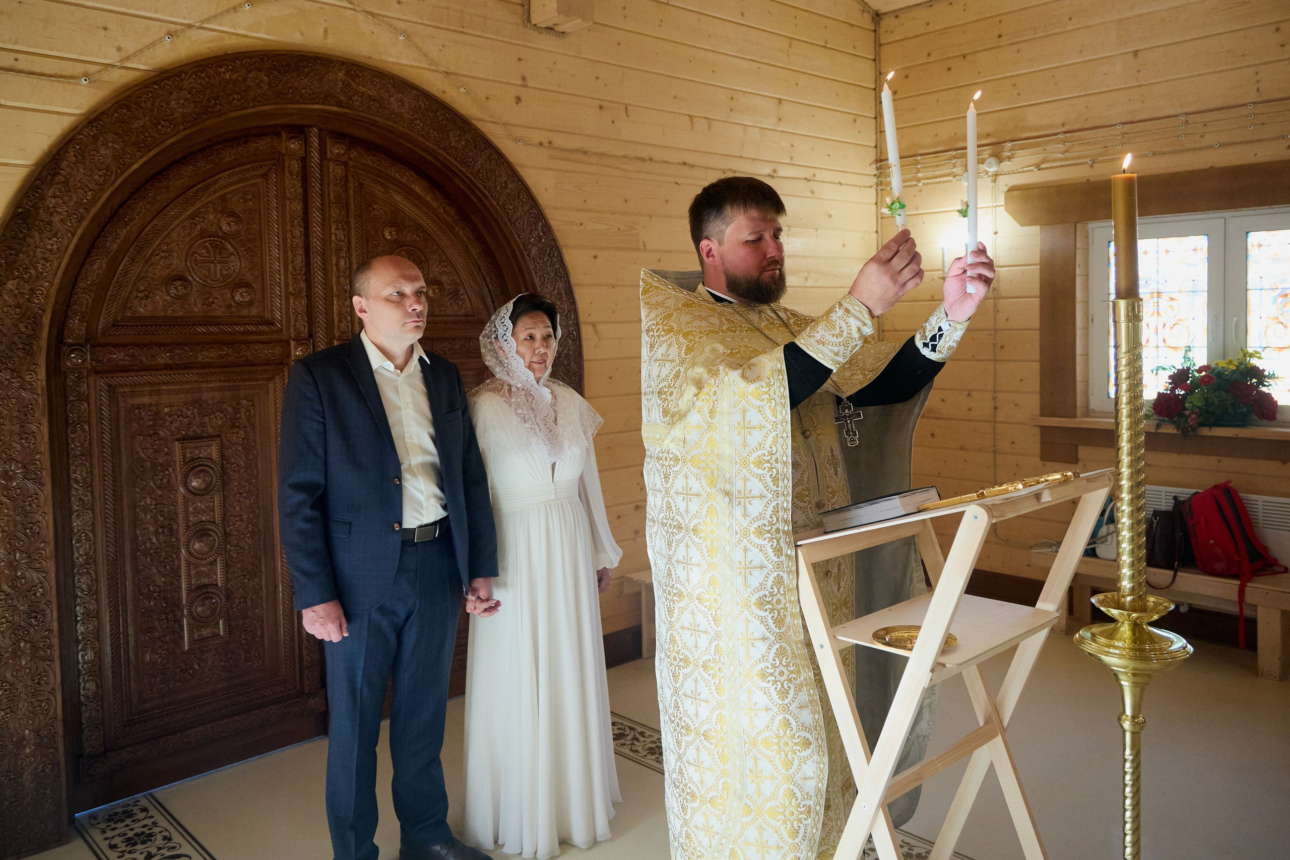 батюшка зажигает свечи в церкви перед венчанием