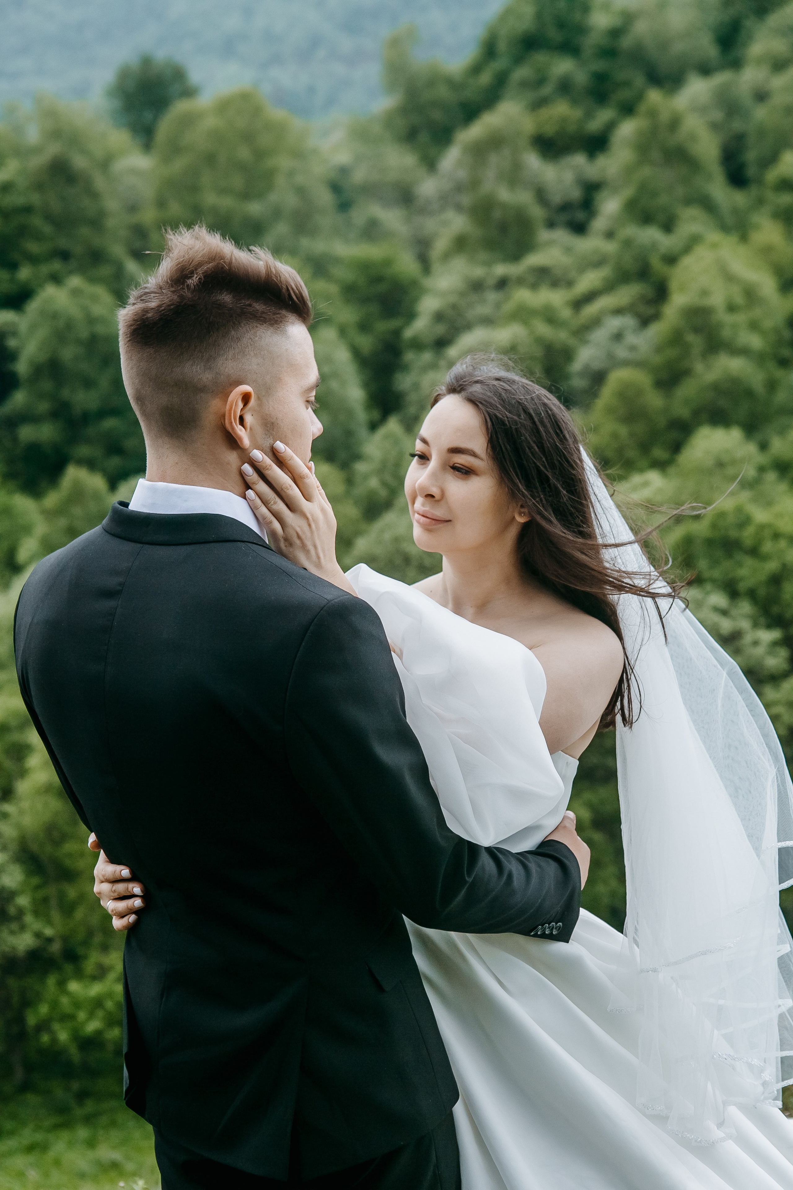 Свадебная церемония, проходящая на открытом воздухе среди величественных гор, с цветочными декорациями и гостями