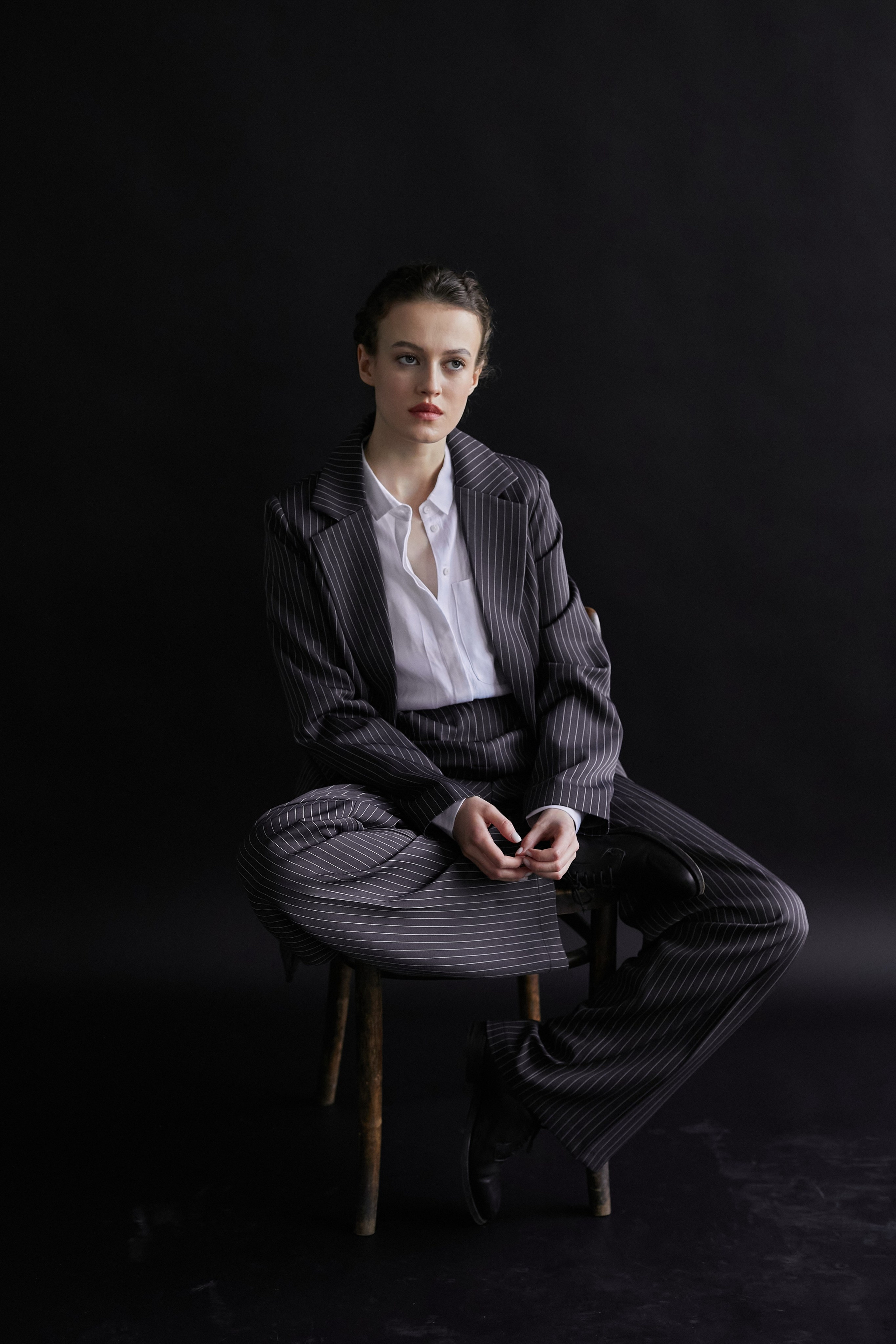Фотограф в Москве. Студия. Студийный портрет. Девушка в пиджаке. Девушка на стуле на черном фоне. Красивая девушка в мужском костюме. Женский портрет.