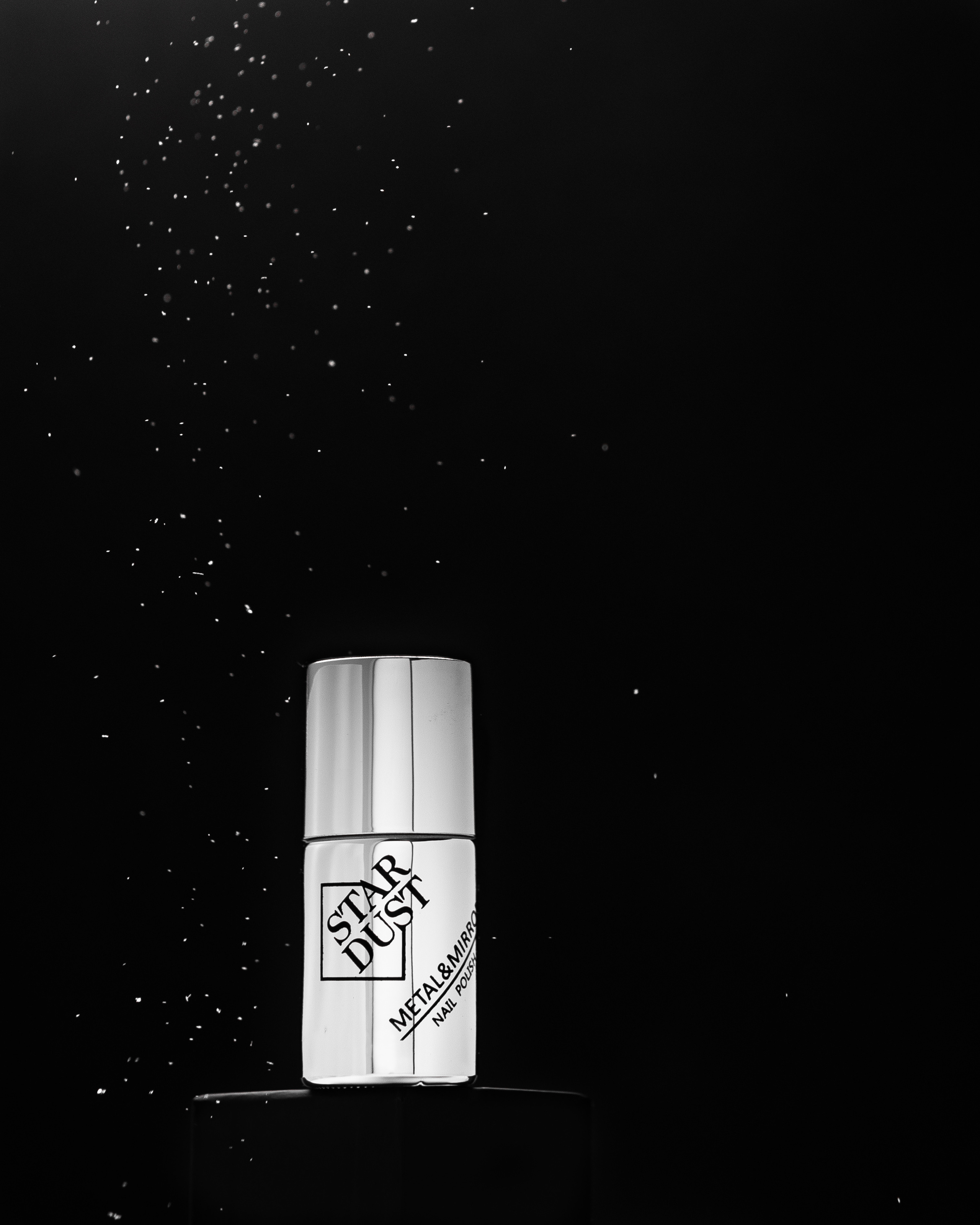 Лак для ногтей серебристого цвета на черном подиуме на черном фоне с летящими блестками